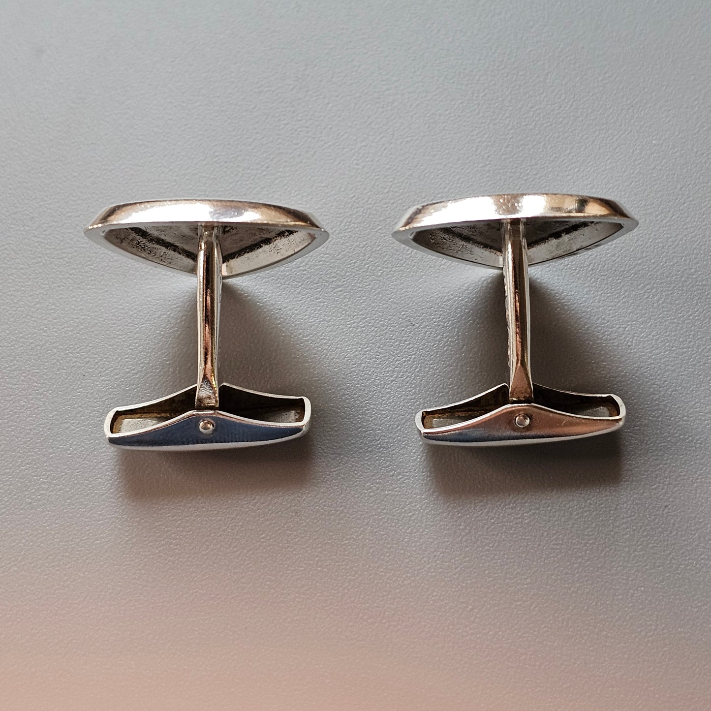 Pair of silver-colored oval cufflinks with T-shaped bars.