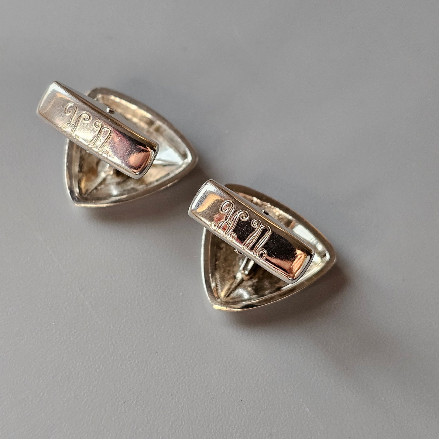 Pair of triangular silver cufflinks with engraved designs.