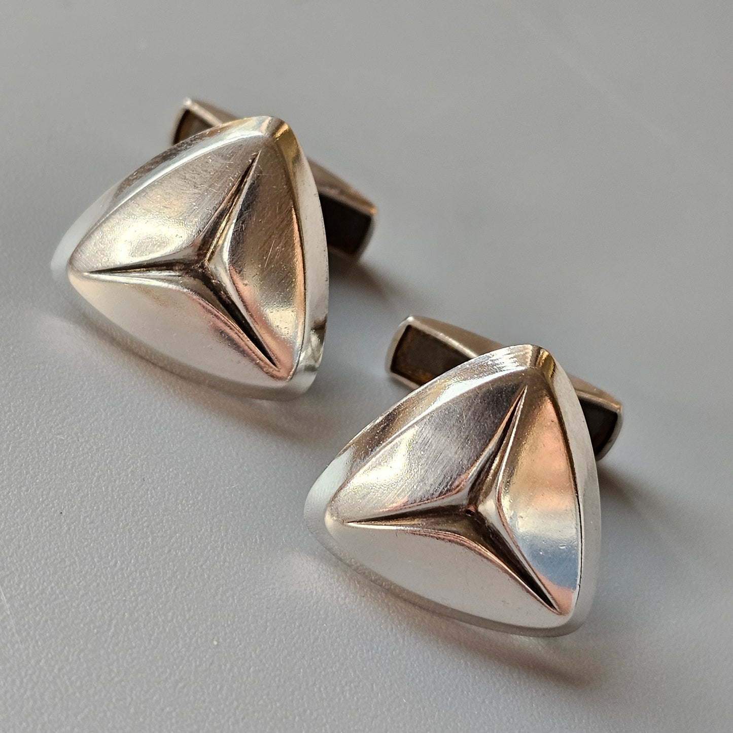 Pair of silver triangular cufflinks with a sleek, modern design.