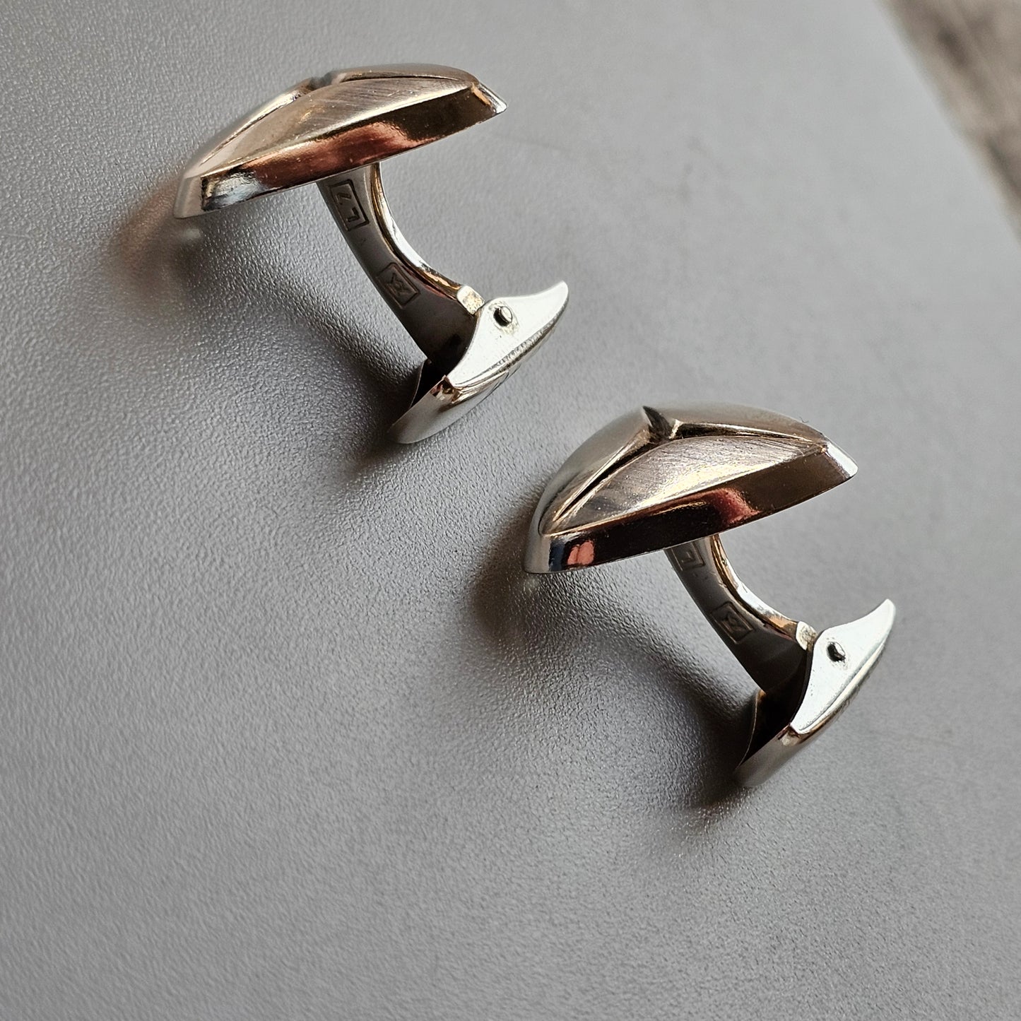 Pair of silver cufflinks shaped like stylized mushrooms.
