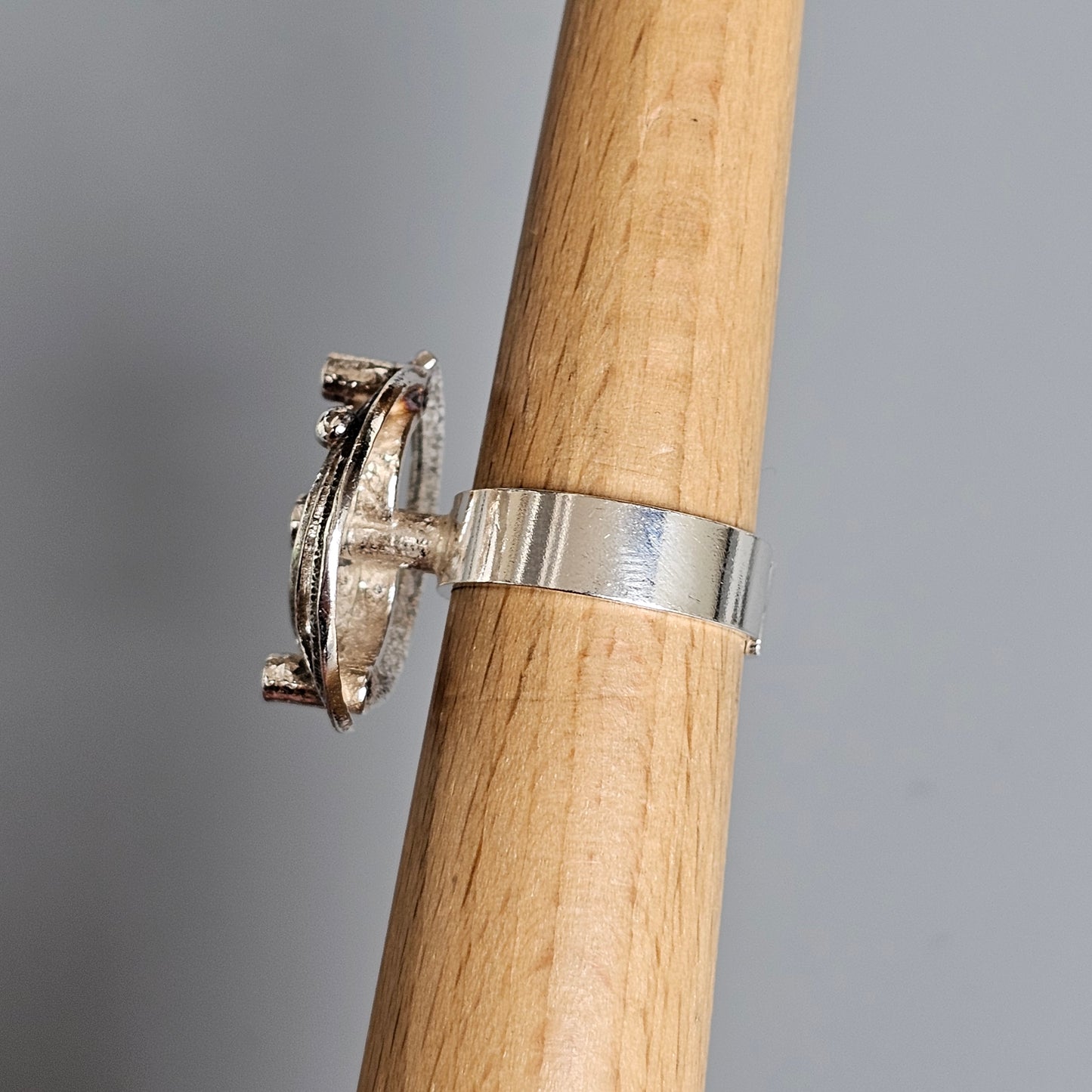 Wooden dowel or rod with two rings around it, one plain metal and one ornate.