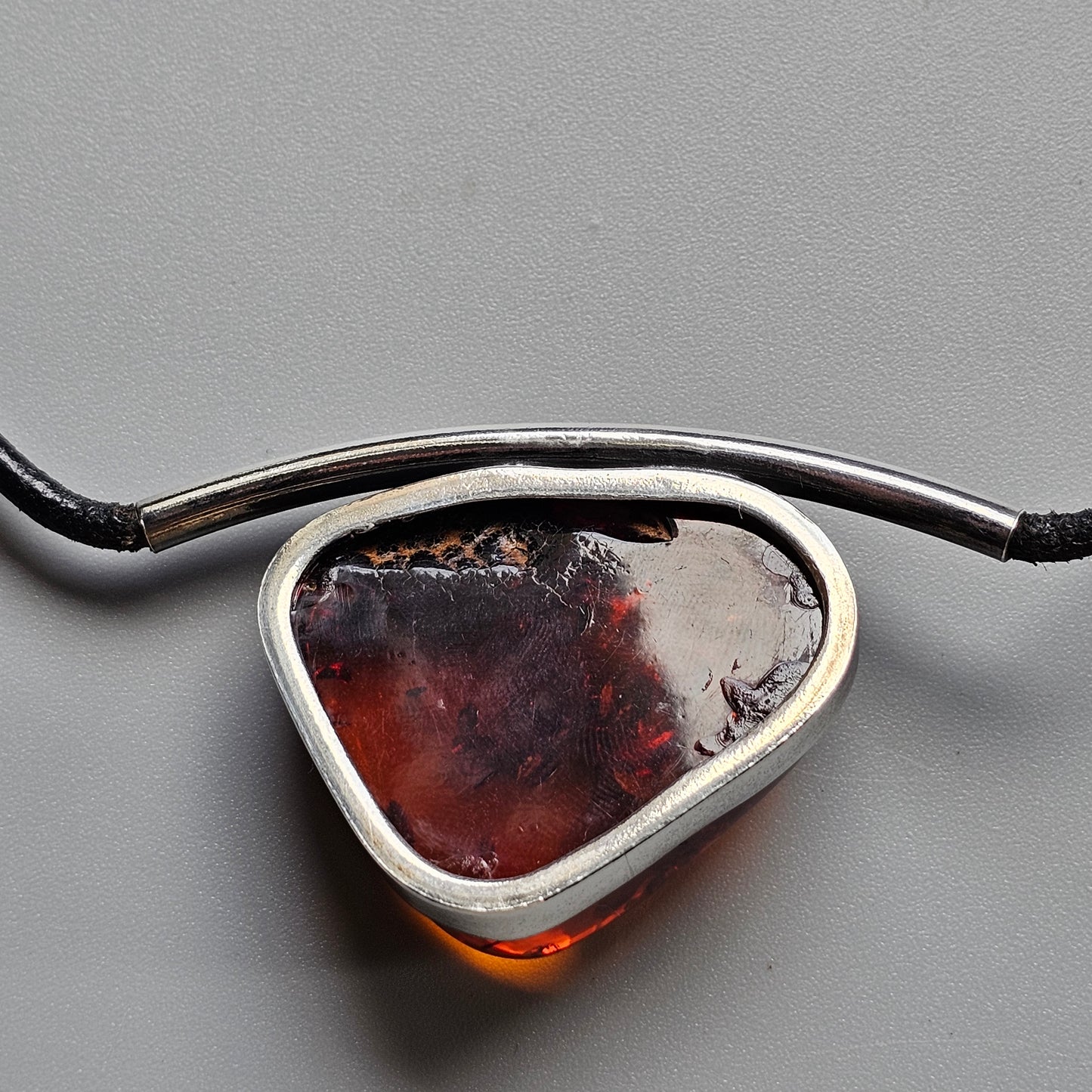 Pendant necklace featuring a triangular amber or resin stone set in a silver bezel.