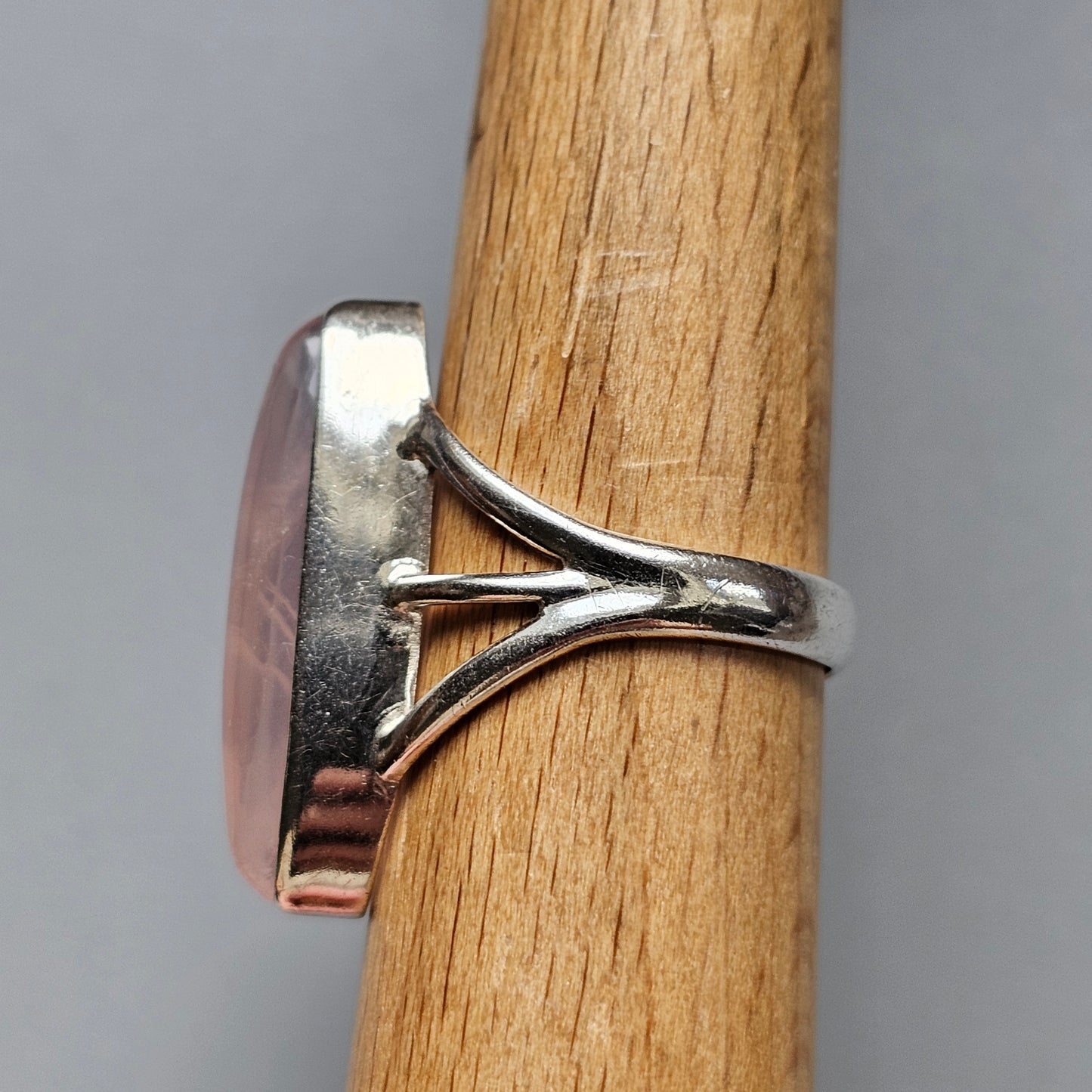 Silver ring with a pink oval gemstone set in a decorative prong setting.