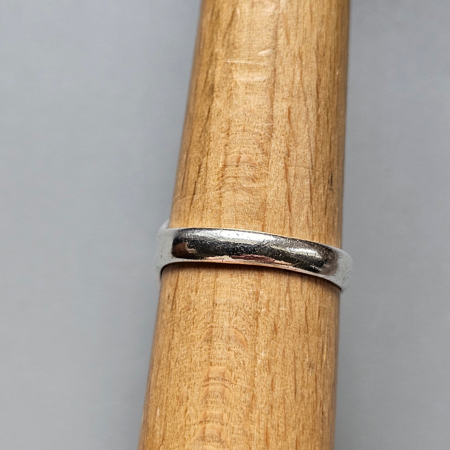 Silver ring encircling a wooden cylinder.