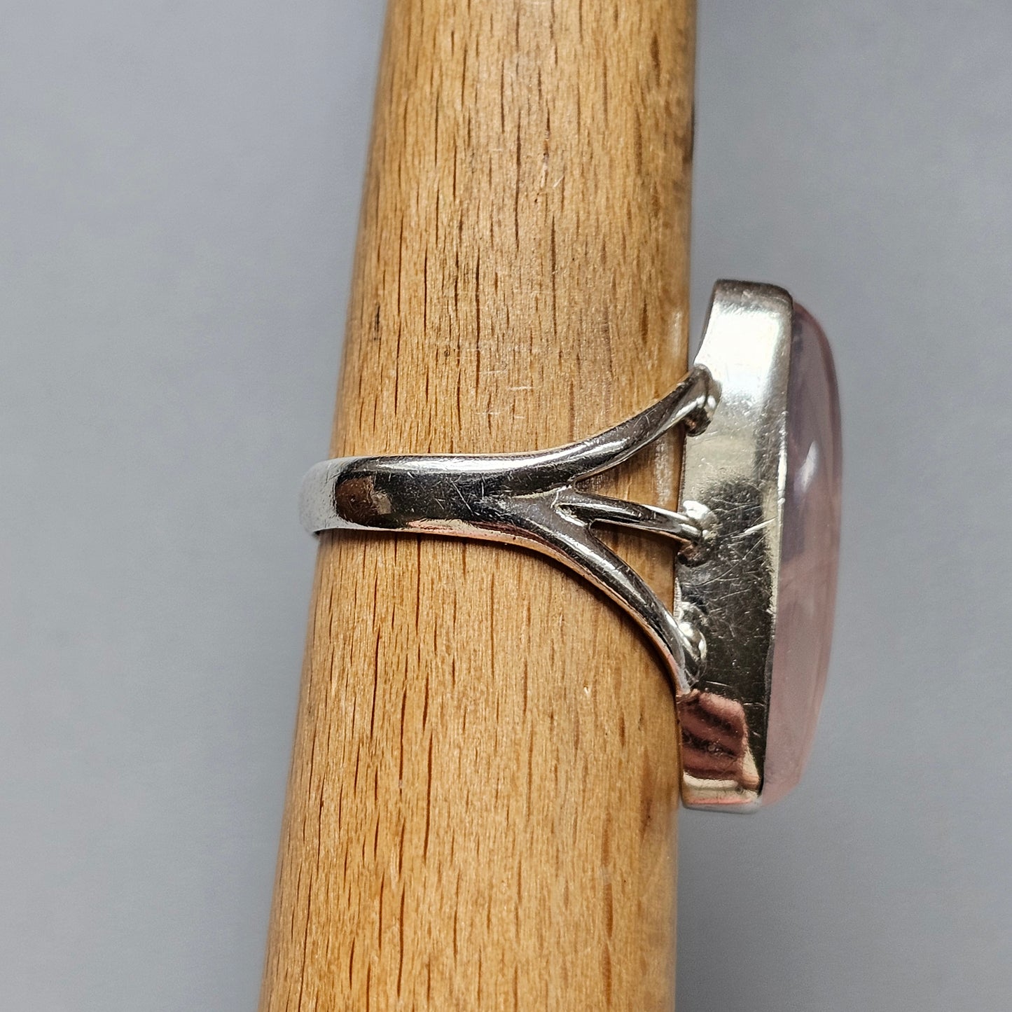 Silver ring with a pink oval gemstone set in a modern, sculptural design.