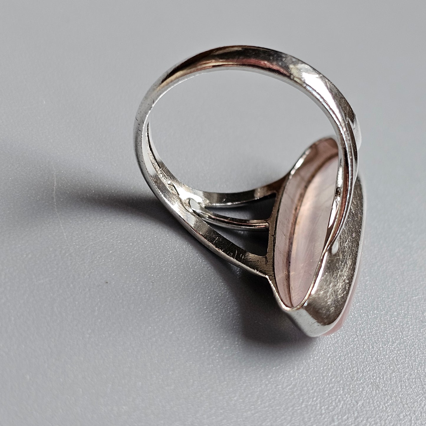 Silver ring with an oval pink gemstone or cabochon set in the center.