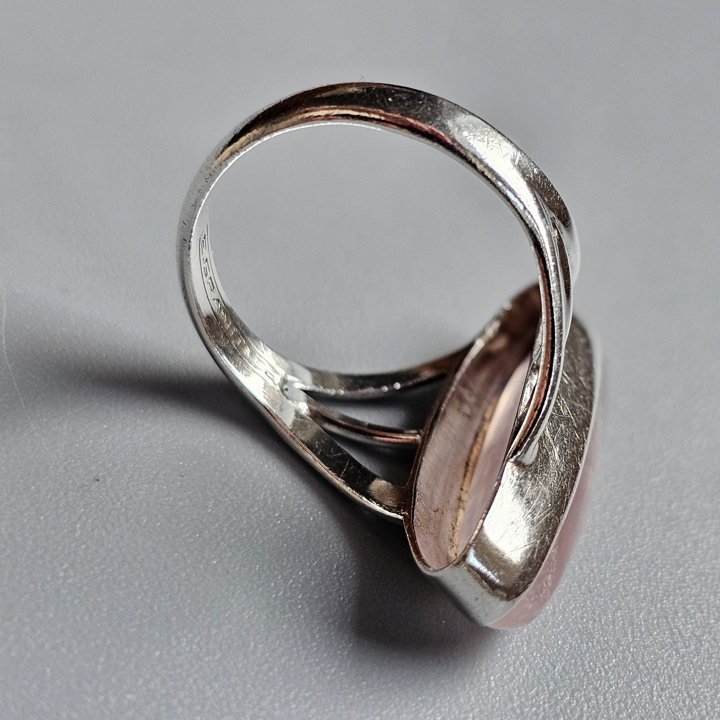 Silver ring with an oval pink stone or gem set in the center.
