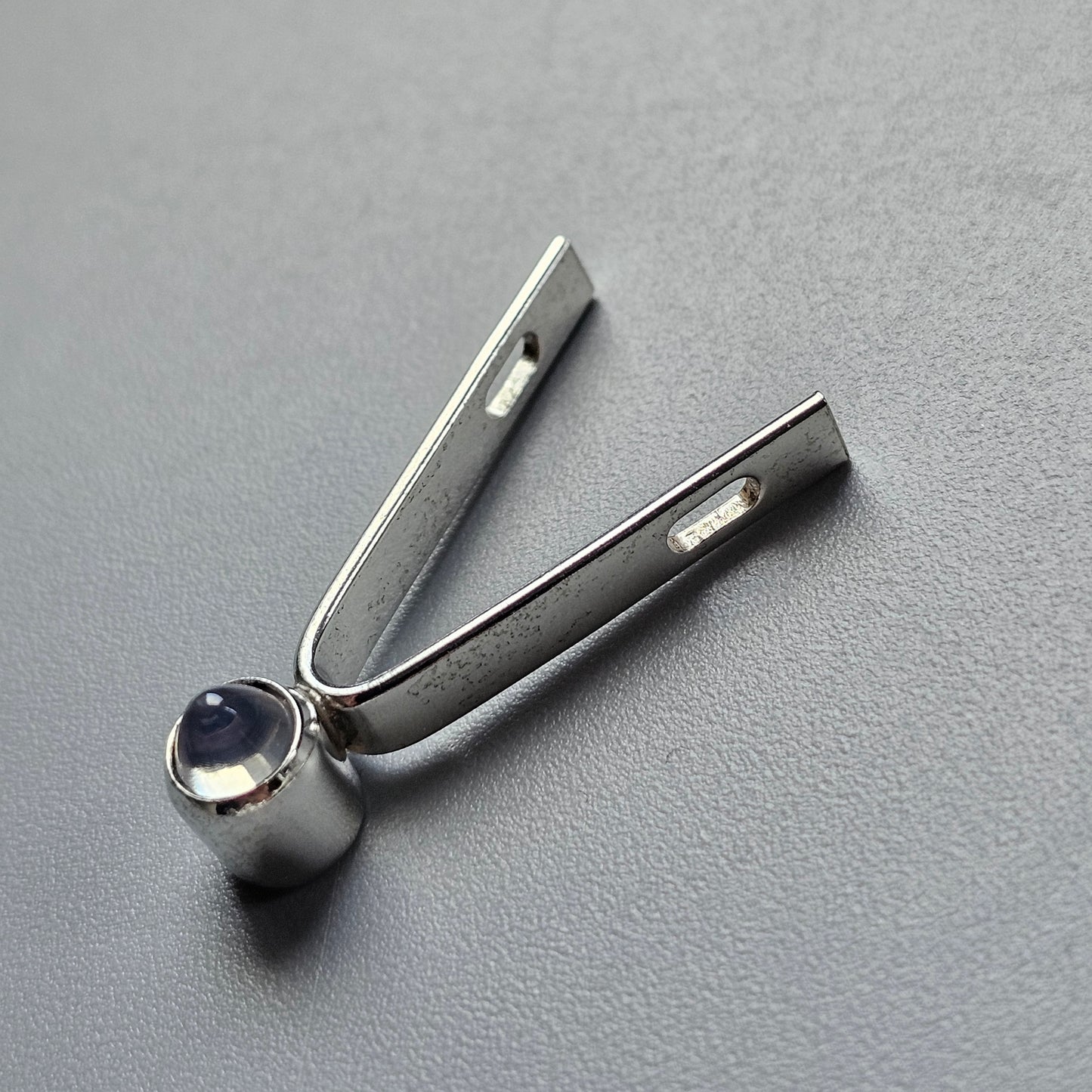 Metal tuning fork with a spherical weight at its base.