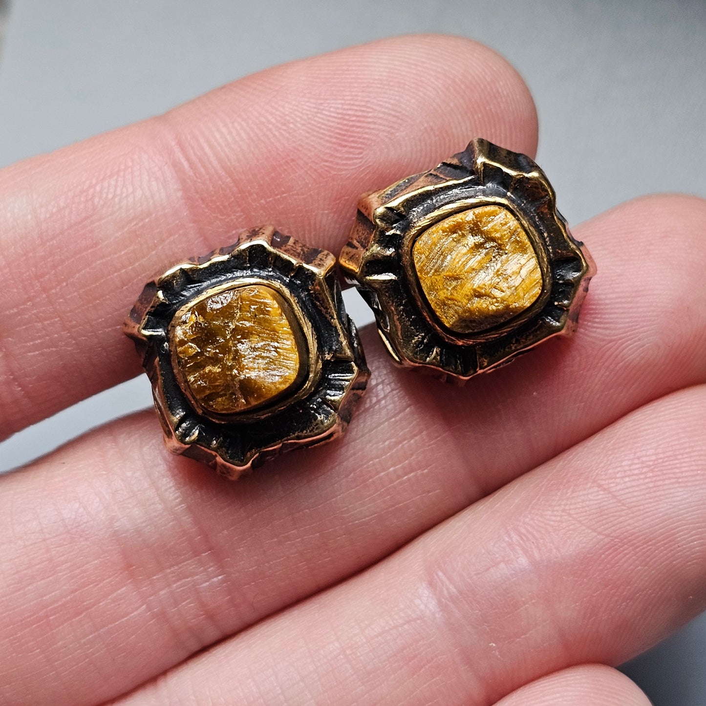 Pair of vintage-style earrings with amber-colored gemstones in ornate metal settings.