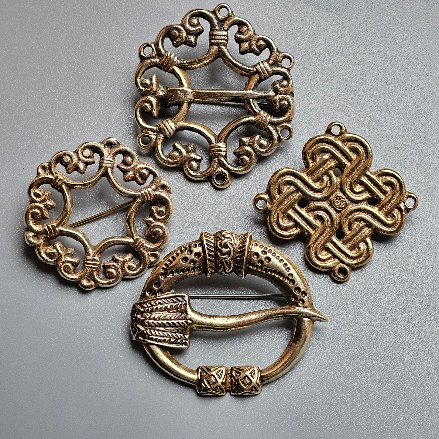 Collection of ornate metallic brooches or pins featuring Celtic-inspired designs.