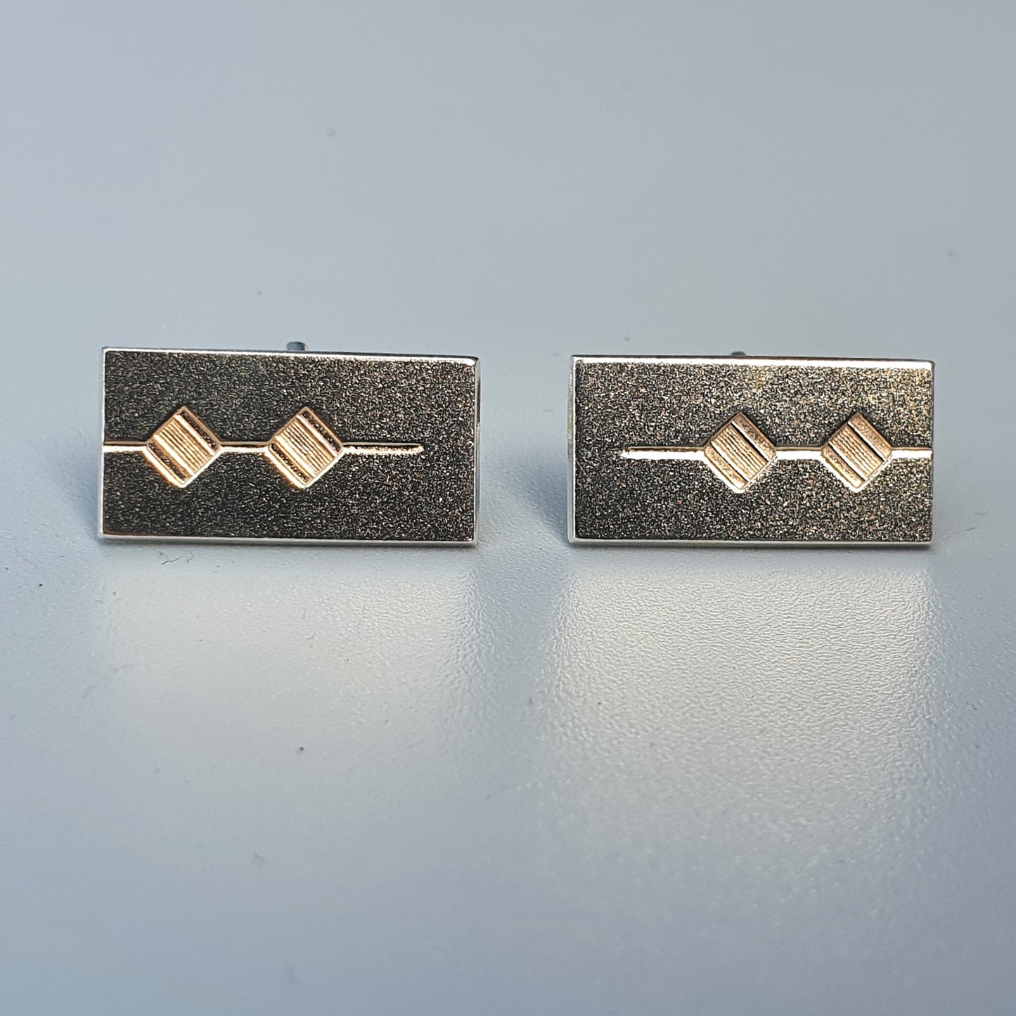 Pair of rectangular silver cufflinks with gold diamond-shaped accents.
