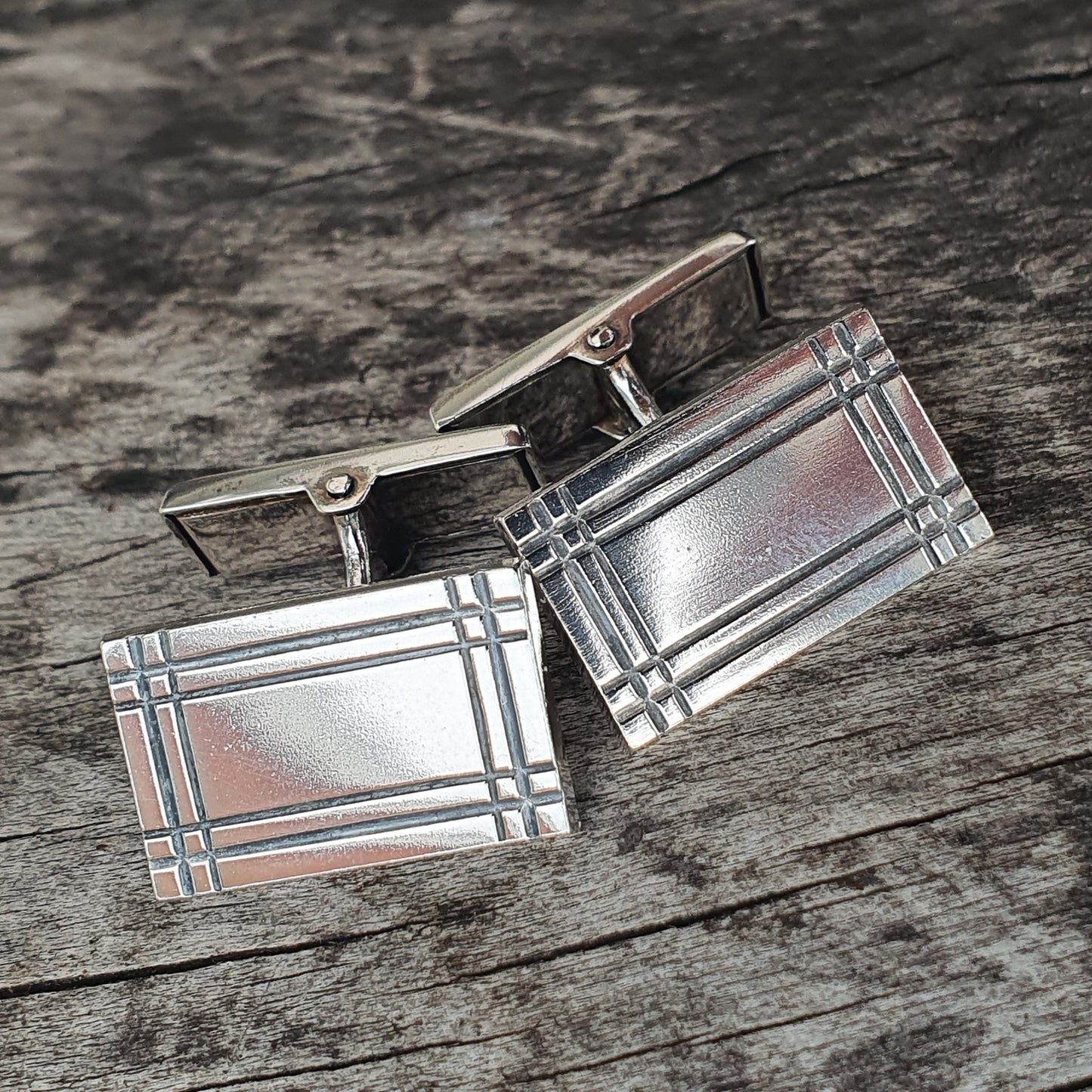 Pair of silver rectangular cufflinks with a geometric pattern.