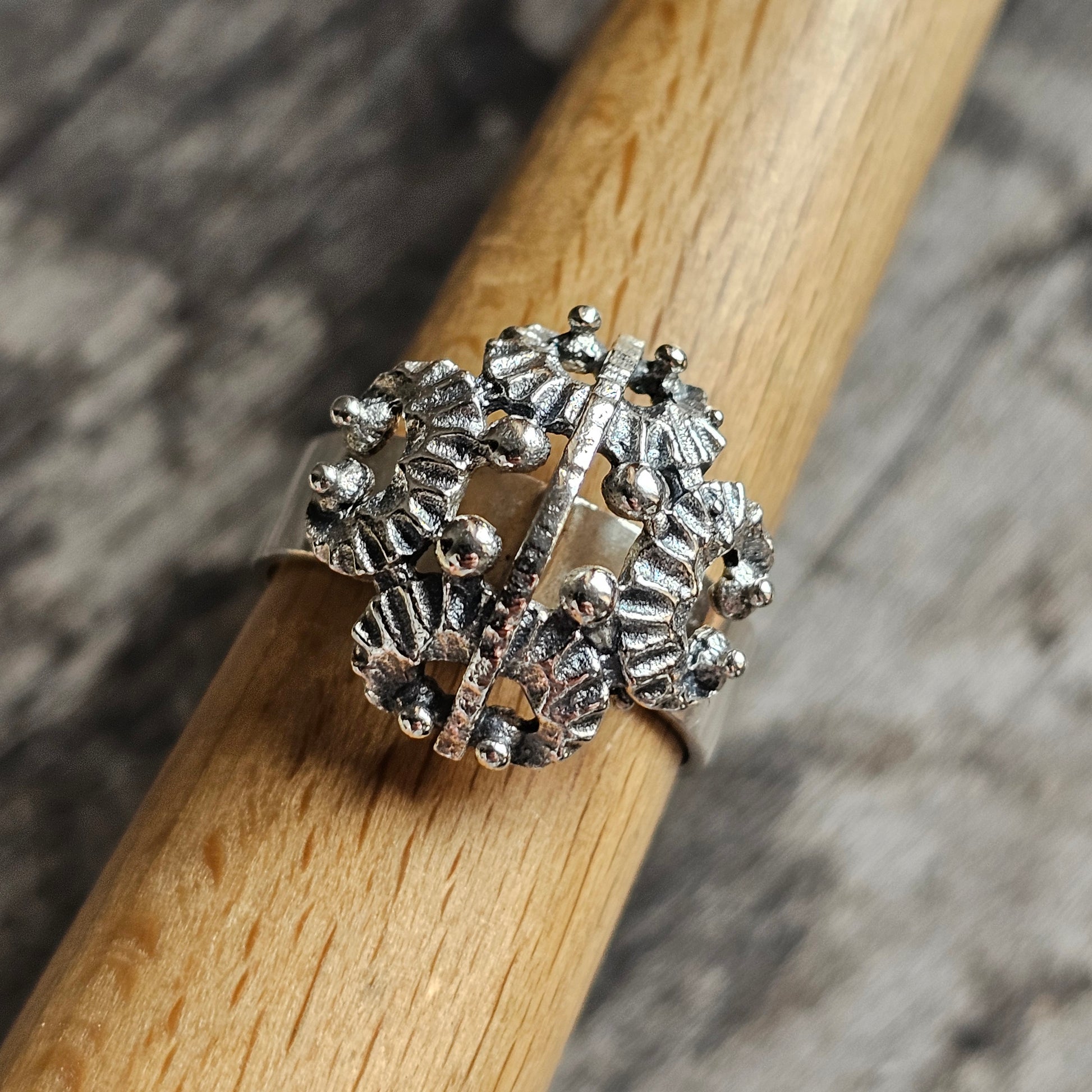 Ornate silver ring with a floral or starburst design.