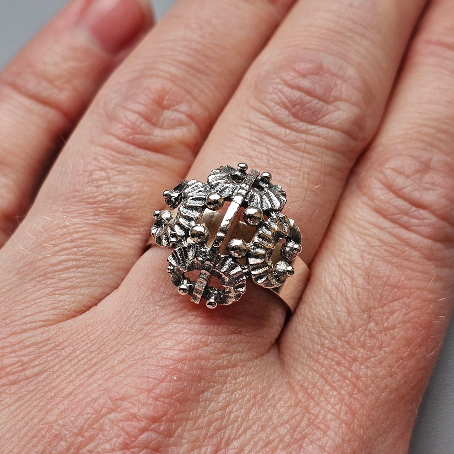 Ornate silver ring with a spherical design featuring floral or starburst patterns.