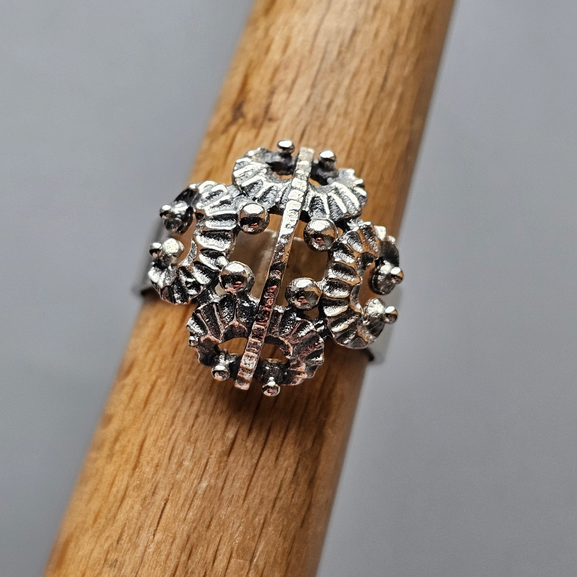 Intricate silver ring with a spherical design composed of floral or snowflake-like patterns.