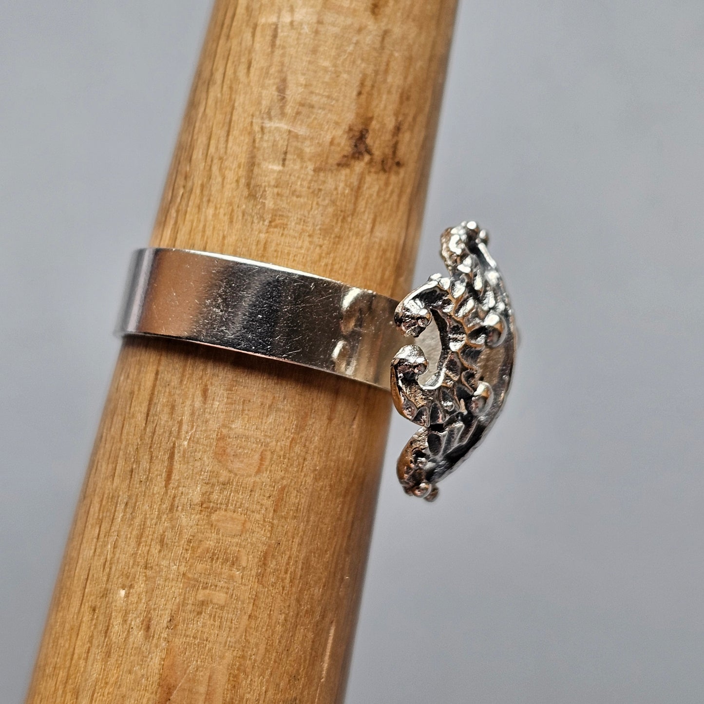 Silver ring with an ornate chameleon-shaped design on top.