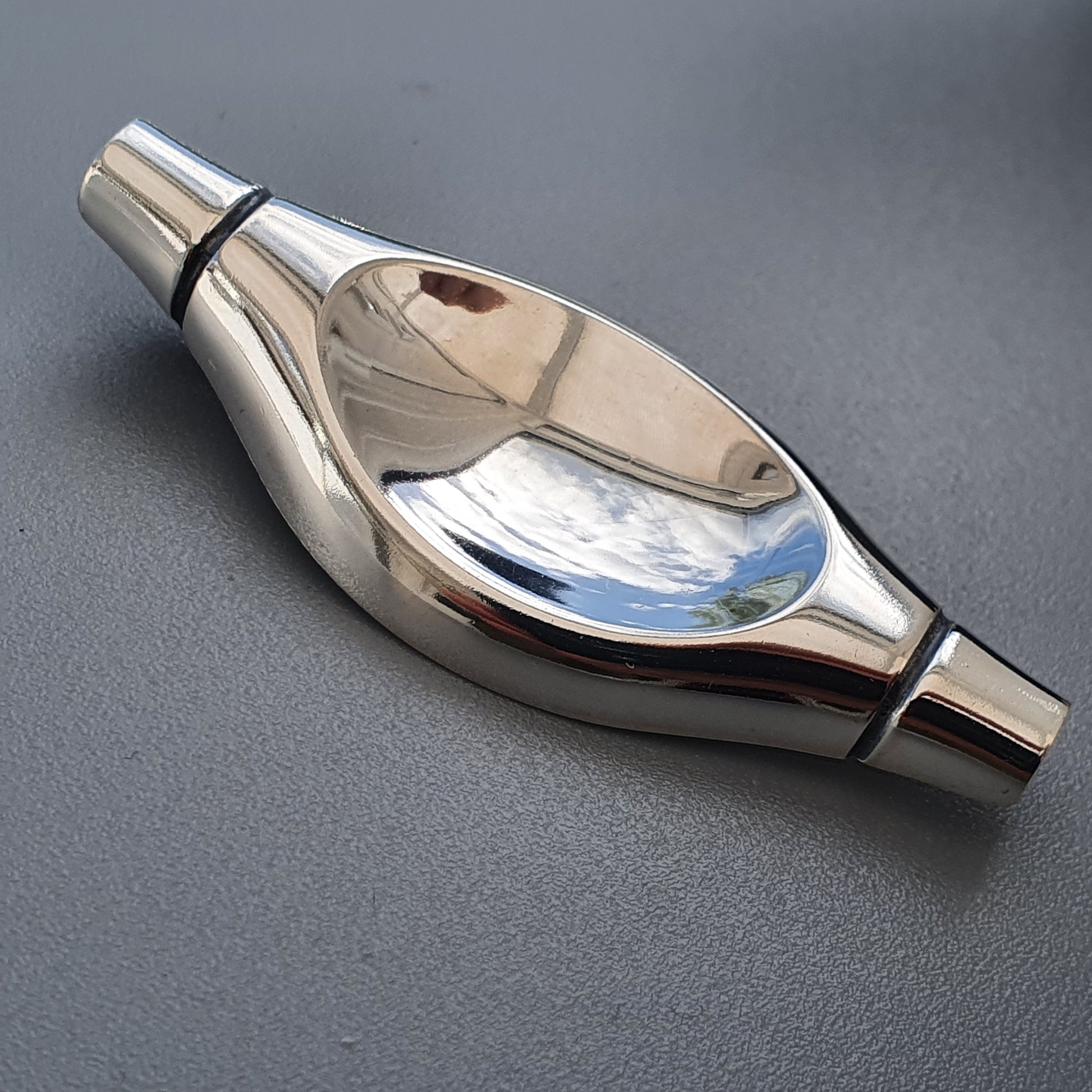 Shiny metallic whistle with a bulbous center and tapered ends.