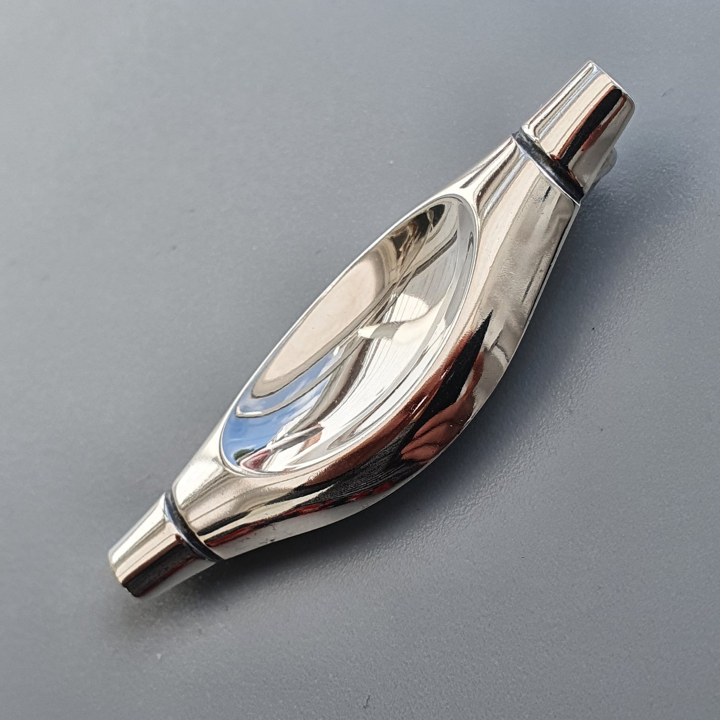 Sleek, polished metal whistle with a curved, teardrop-shaped body.