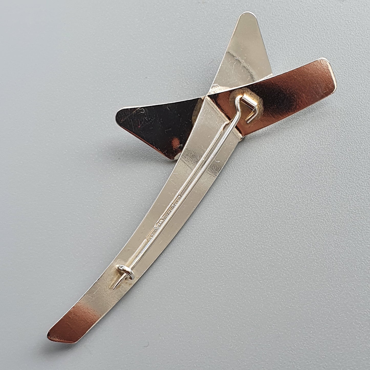 Modernist brooch or pin with angular metallic shapes in silver, copper, and black tones.