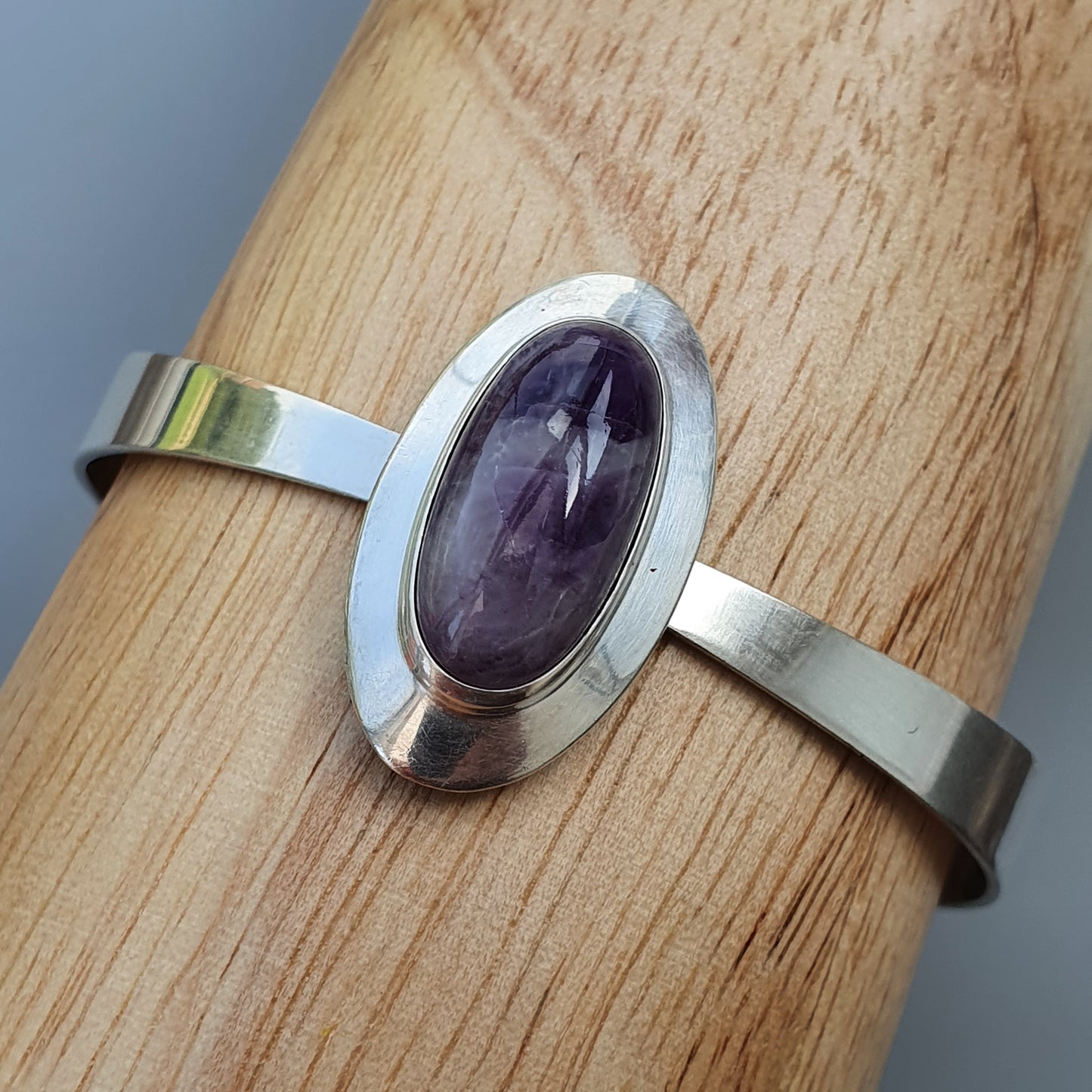 Silver bracelet with an oval purple gemstone centerpiece.