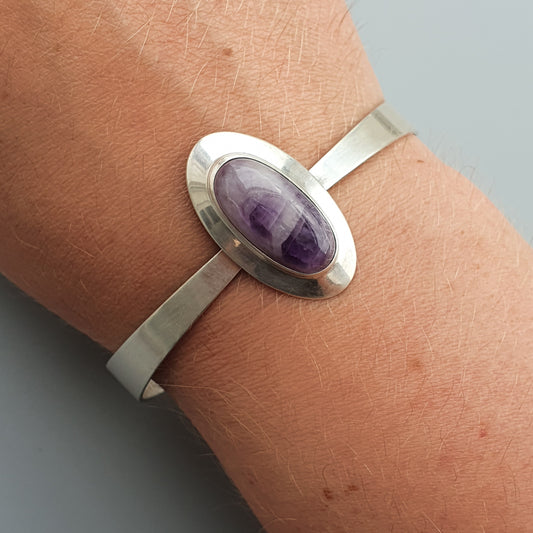 Silver bracelet featuring an oval purple gemstone.