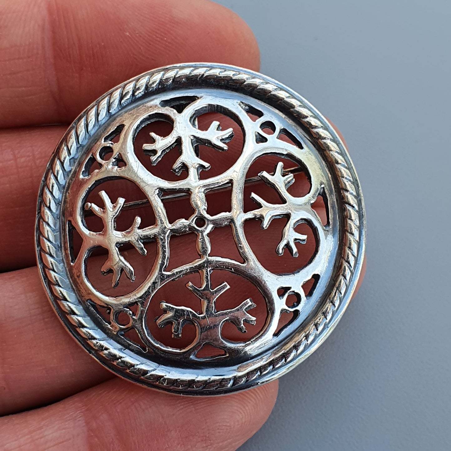 Ornate silver brooch or pendant with intricate Celtic-inspired knotwork design.