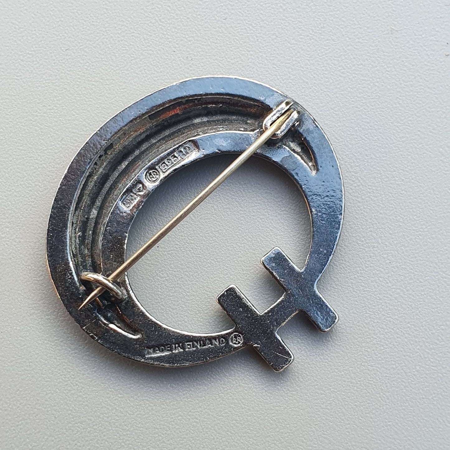 Silver brooch or pin shaped like a hammer and sickle symbol.