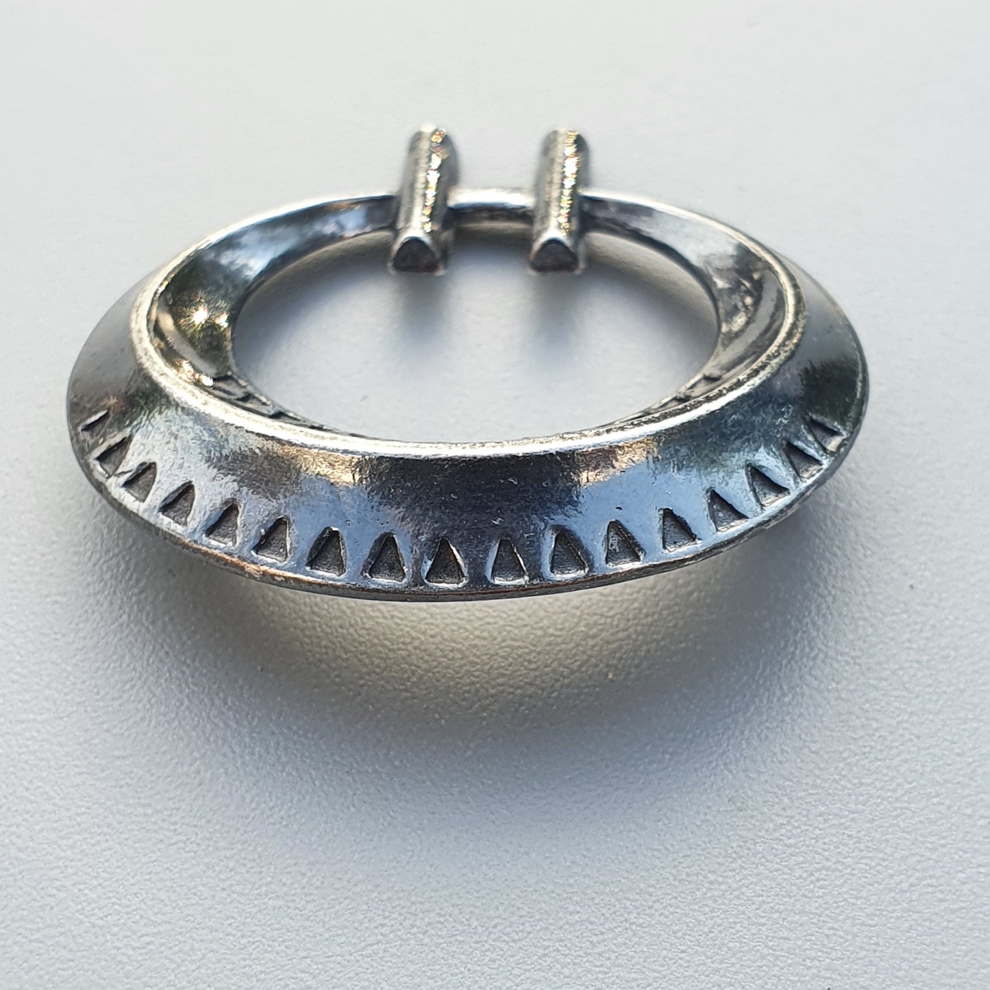 Silver septum ring with decorative triangular cutouts along the outer edge.