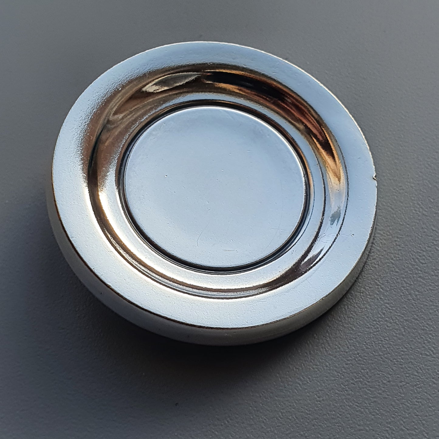 Circular metal ring with a white outer edge and reflective inner surface.