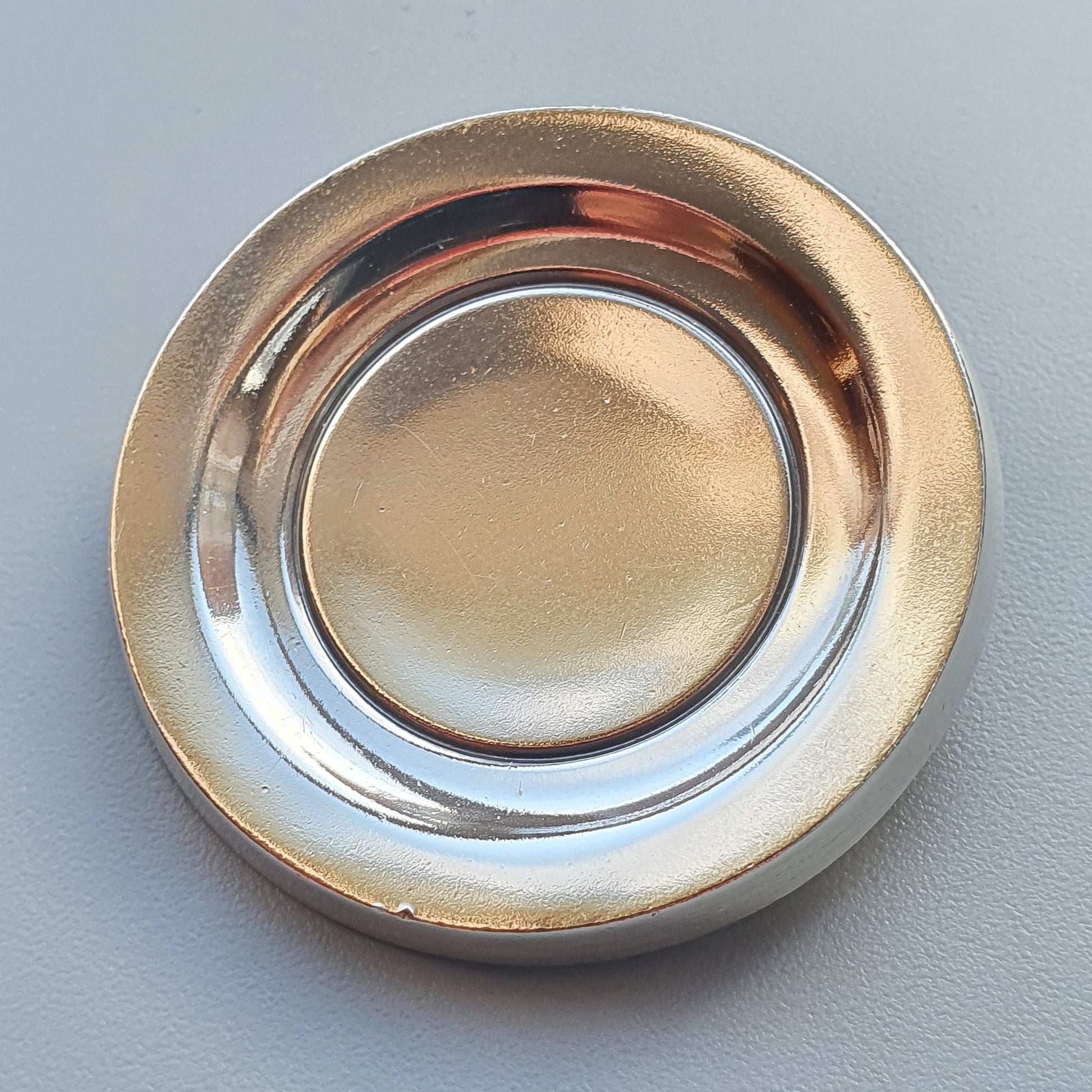 Metallic circular plate or dish with a reflective surface and raised rim.