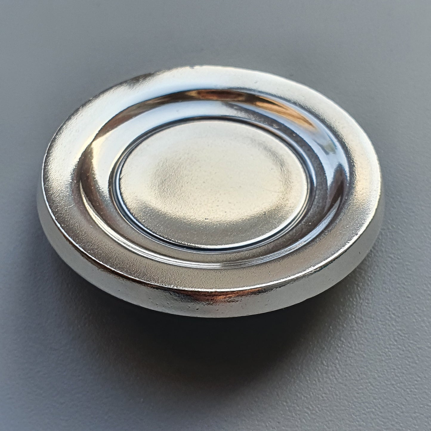 Circular metal plate or dish with a raised rim and slightly recessed center.