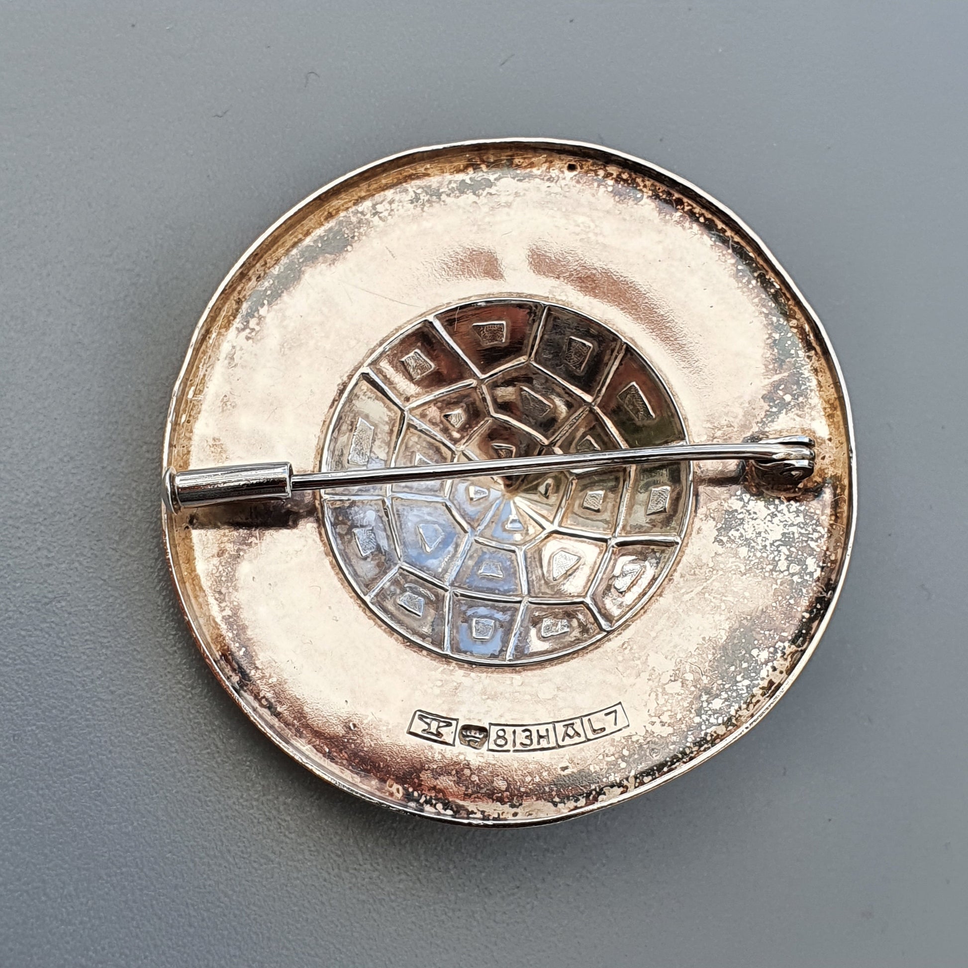 Circular silver ashtray with a segmented design and central crossbar.