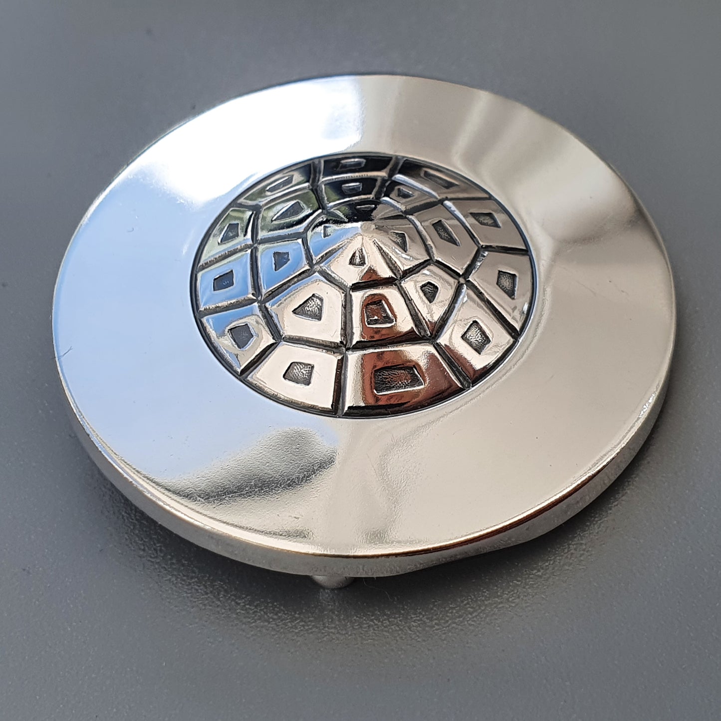 Circular metal drain cover with a patterned dome-shaped grate.