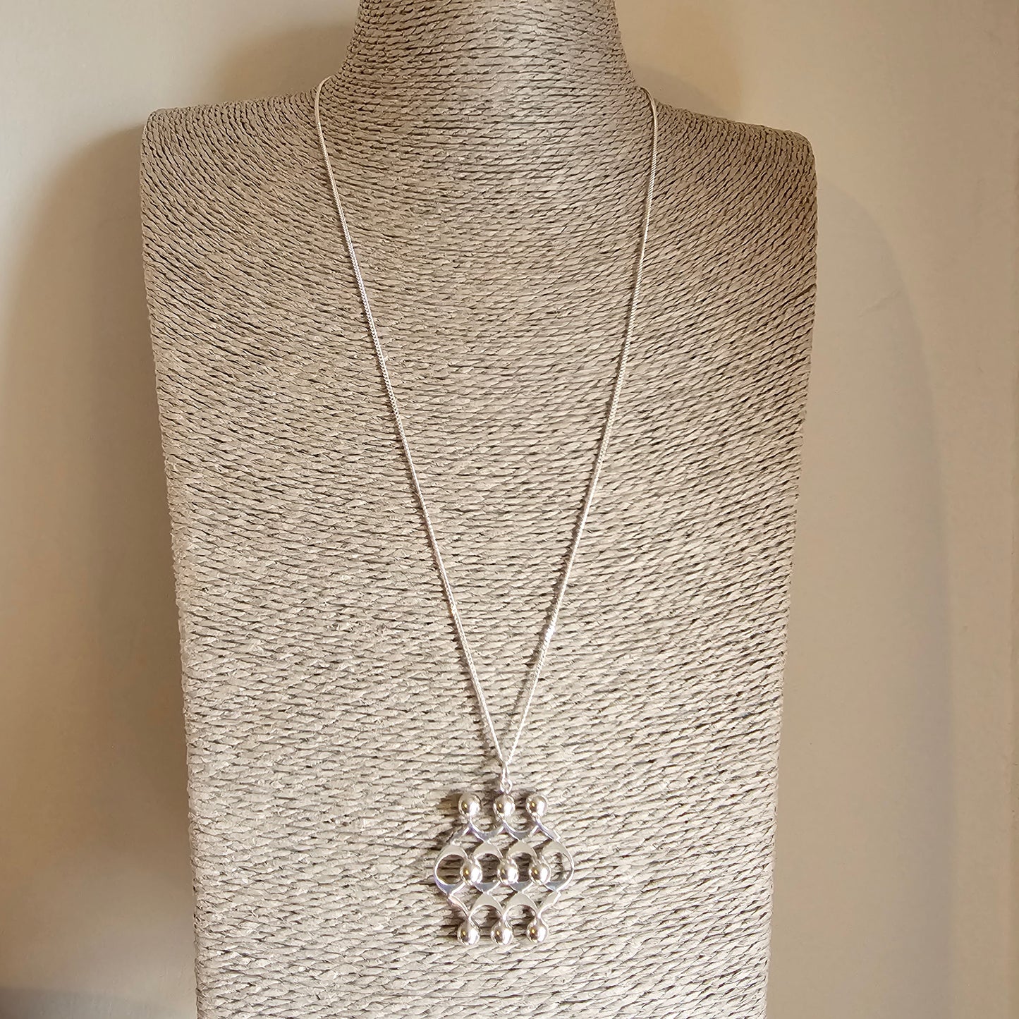 Silver pendant necklace with a geometric design featuring multiple circular elements.