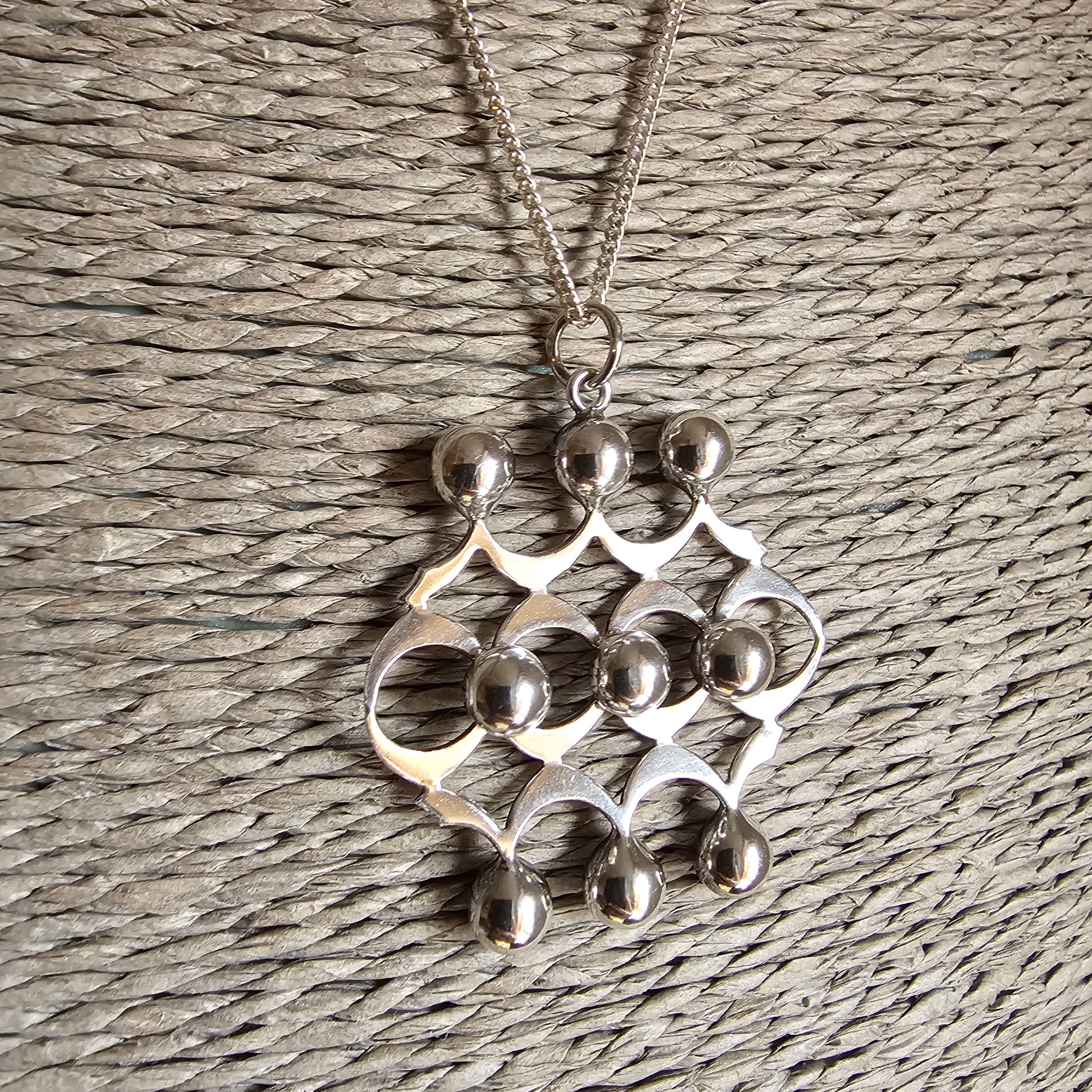 Silver pendant necklace with an abstract geometric design featuring interconnected circles and curves.