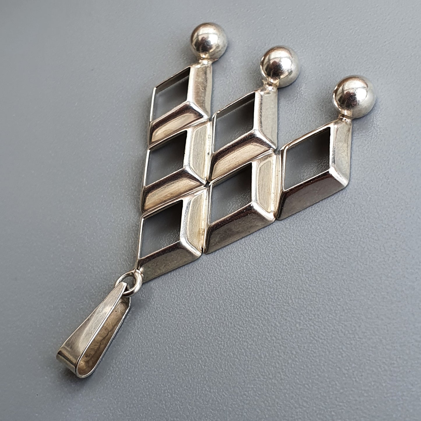 Geometric silver brooch with interlocking diamond shapes and spherical tops.