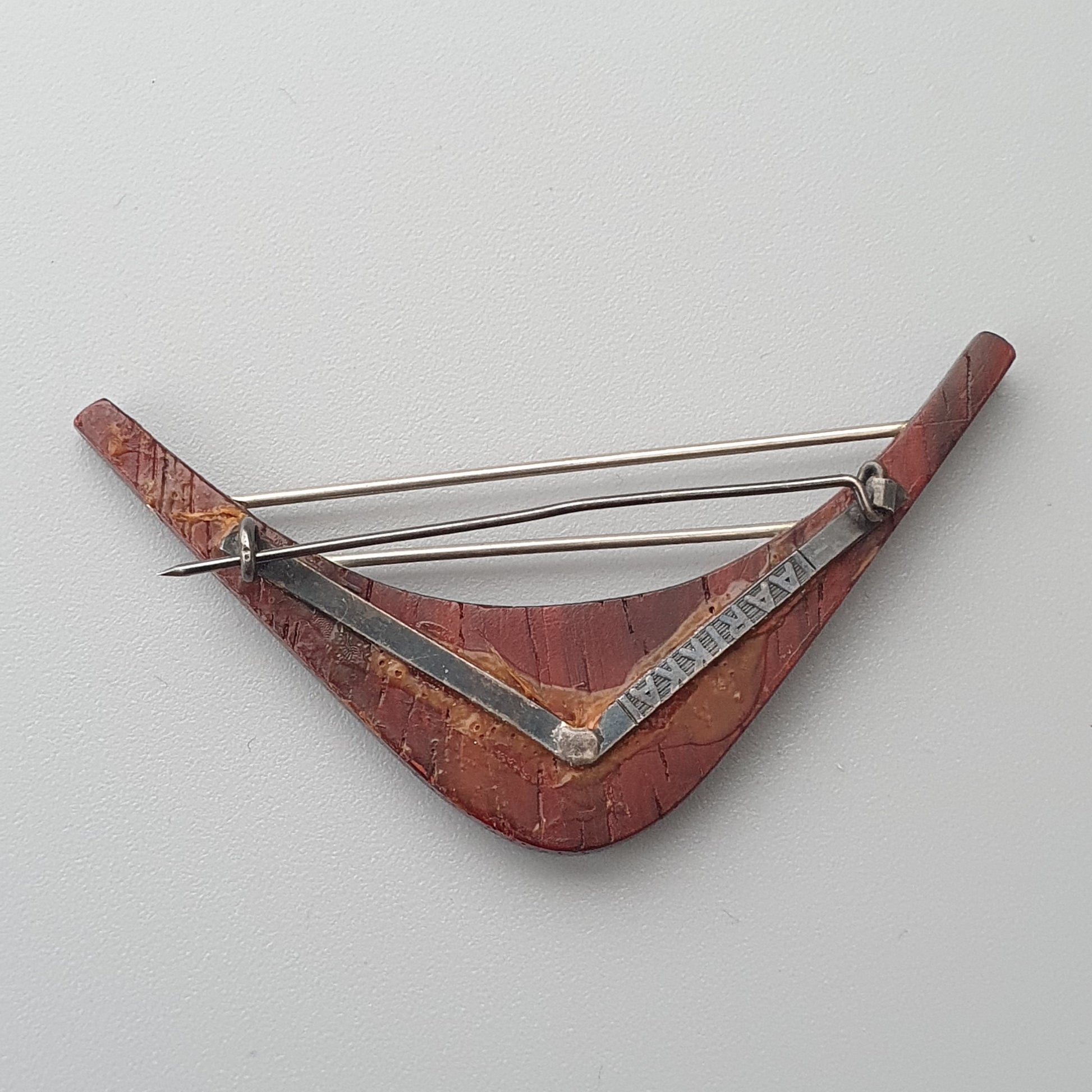 Triangular red musical instrument with metal strings, resembling a small harp or lyre.