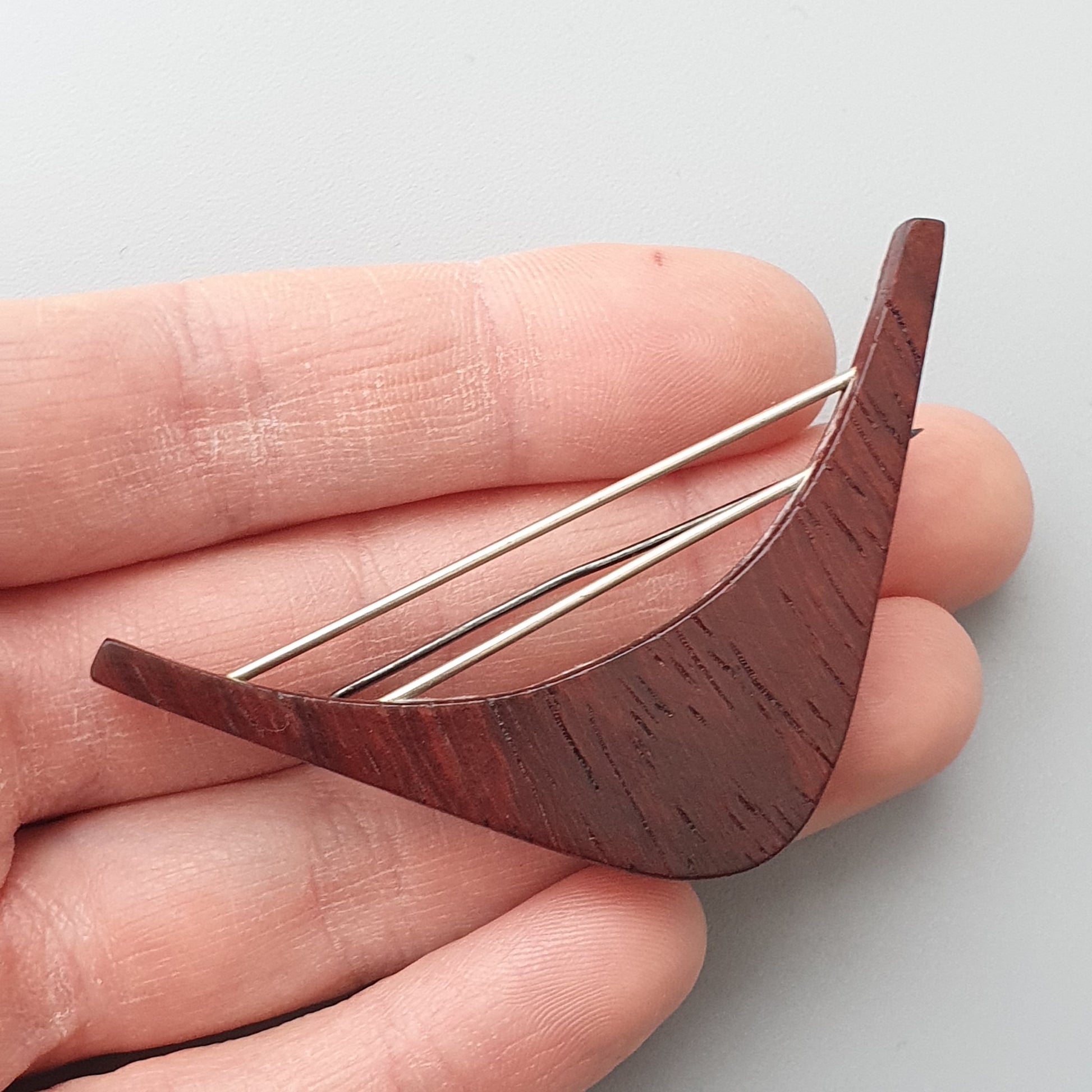 Wooden bird-shaped hair pin or brooch with metal prongs.