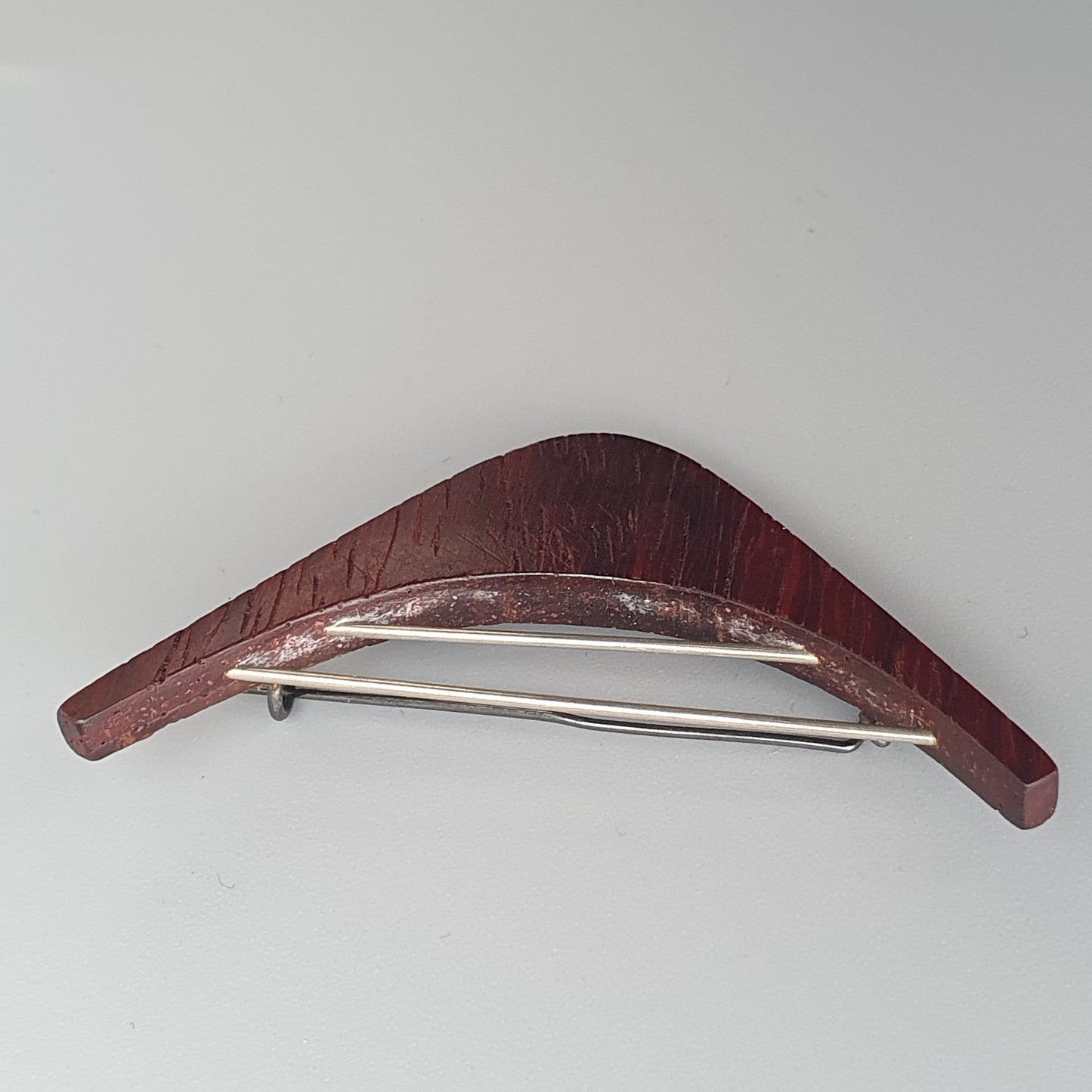 Curved wooden hair clip or barrette with a metal clasp.