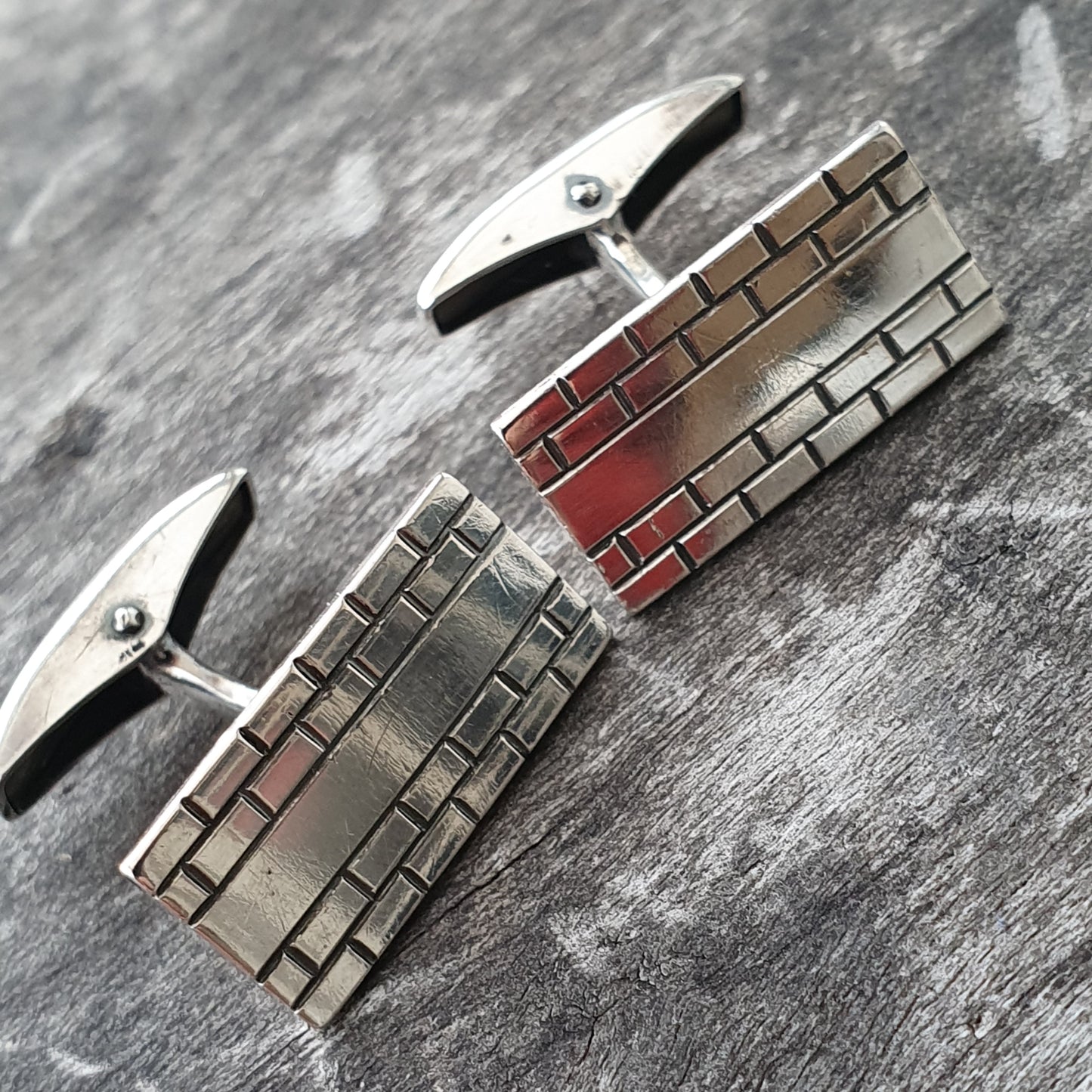 Pair of rectangular silver cufflinks with a brick-like pattern design.