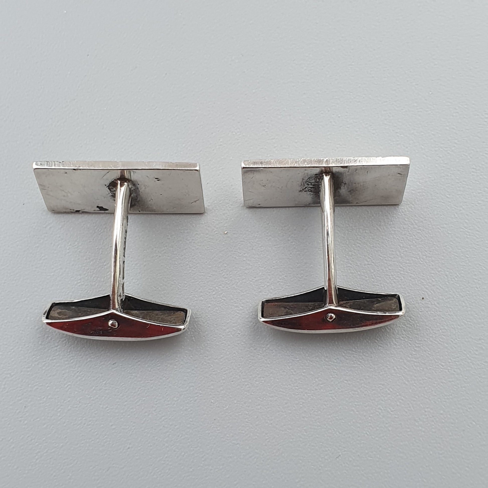 Pair of silver cufflinks with red and black enamel accents.