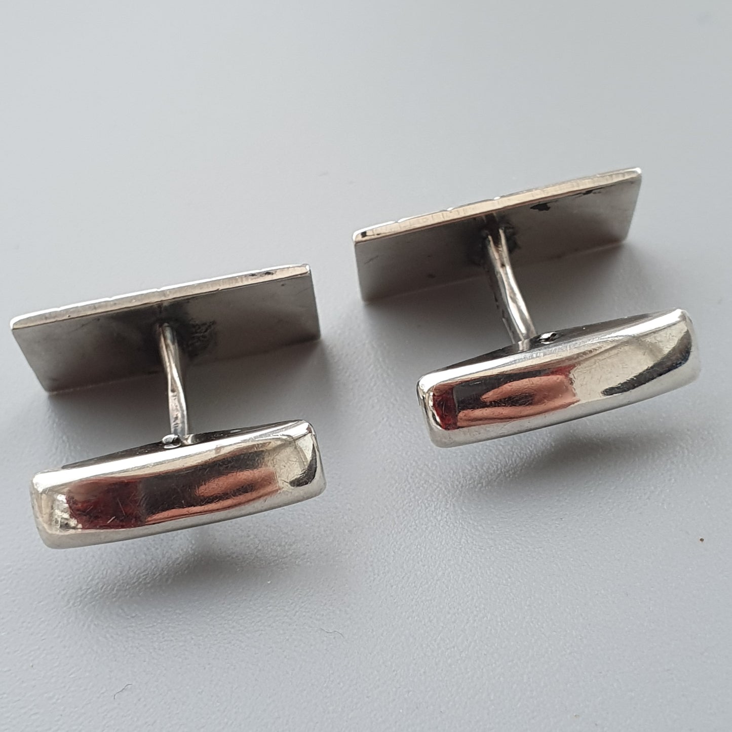 Pair of silver cufflinks with rectangular faces and copper-colored accents.