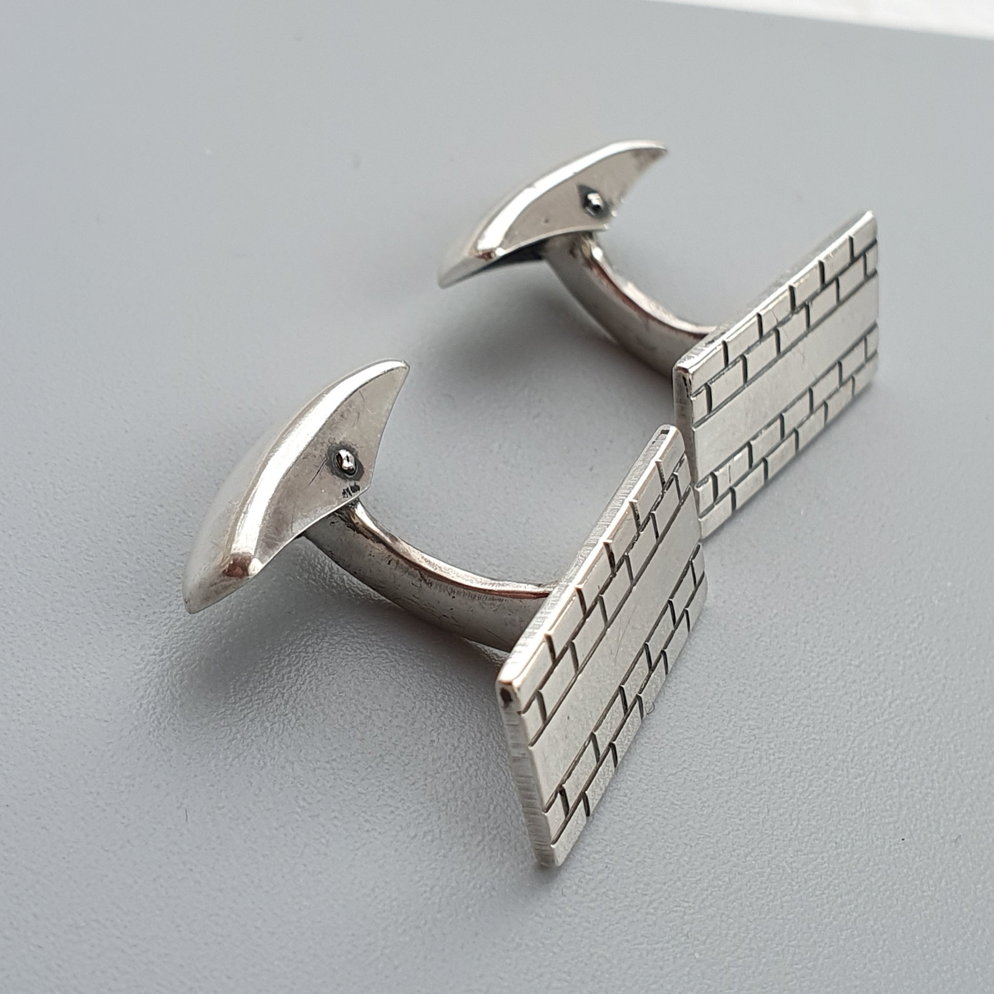 Pair of silver rectangular cufflinks with a brick pattern design.