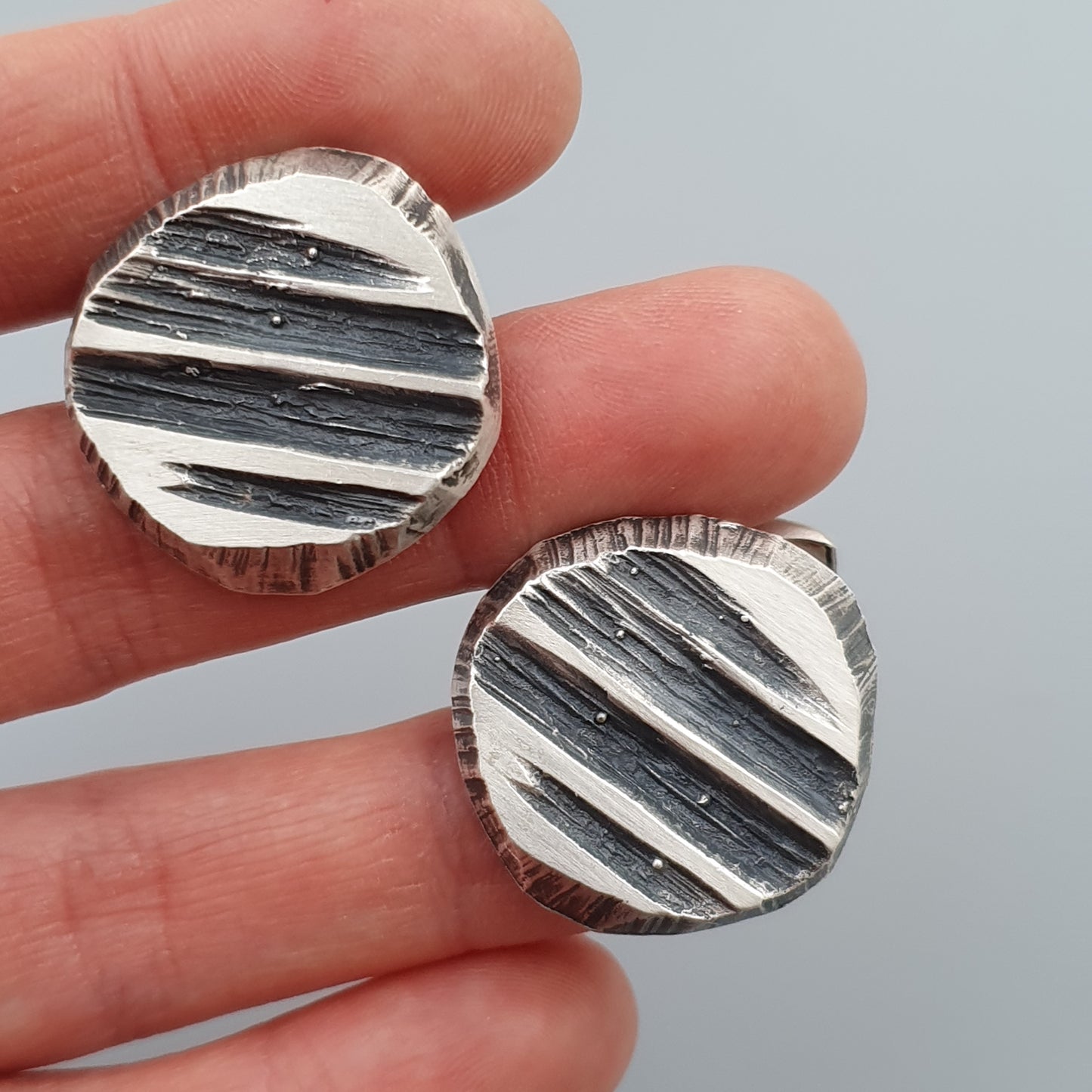 Two circular earrings or pendants with a striped black and white pattern.