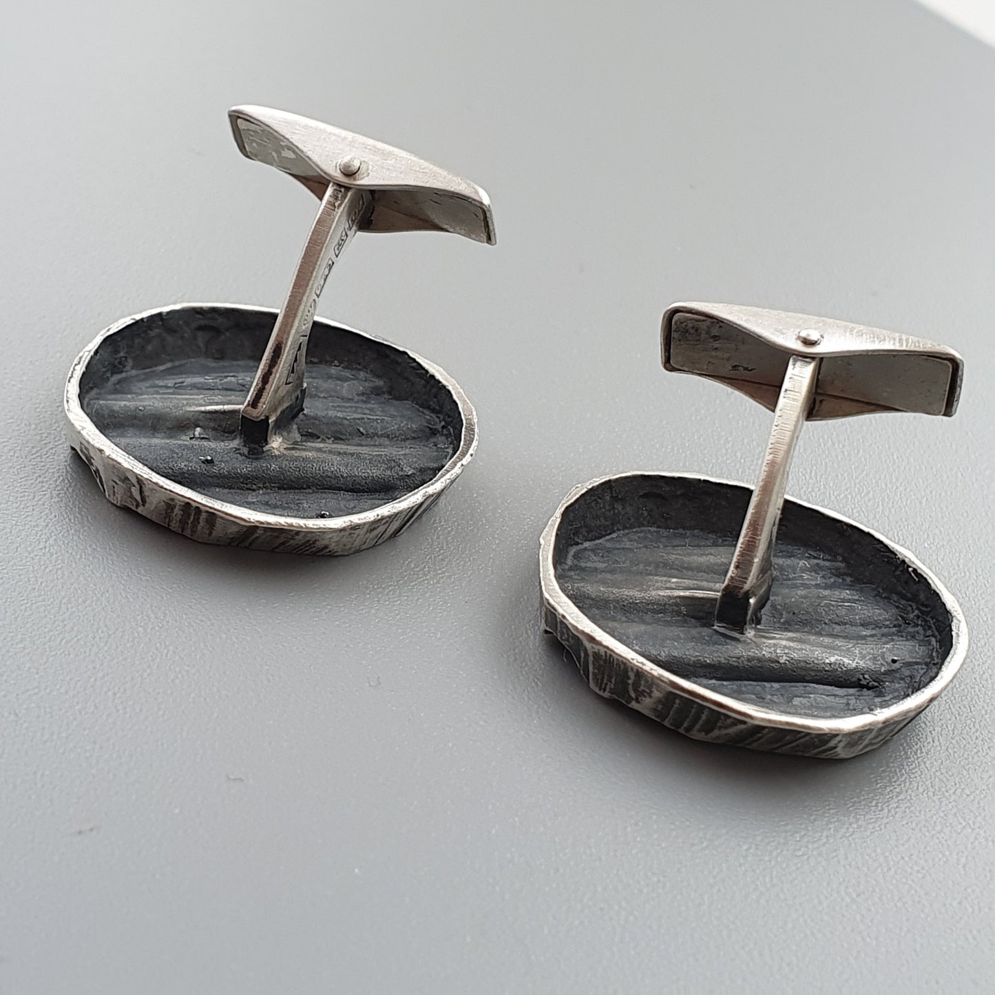 Pair of silver cufflinks with oval-shaped bases and upright posts.