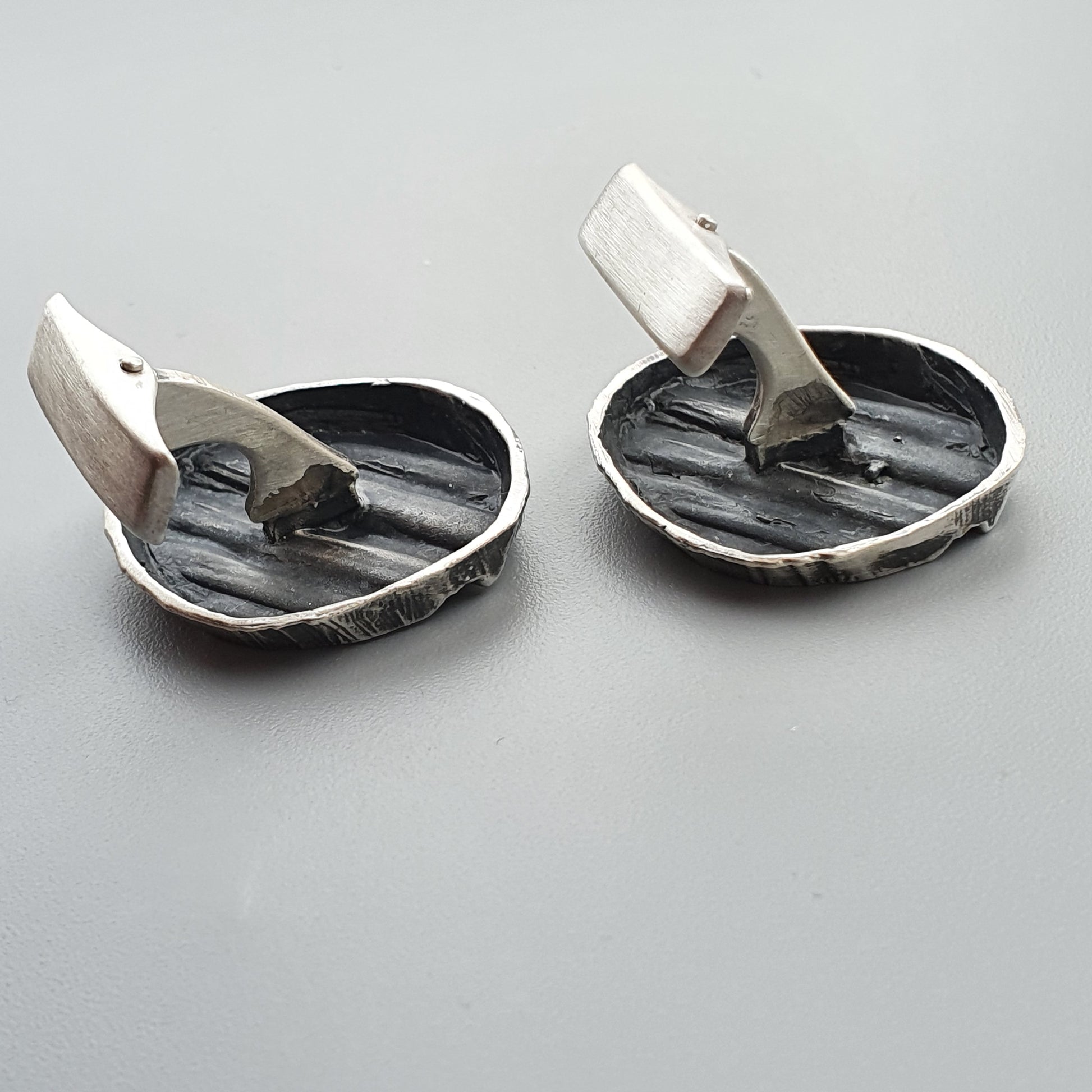 Pair of silver cufflinks with hinged backs and oval-shaped faces.