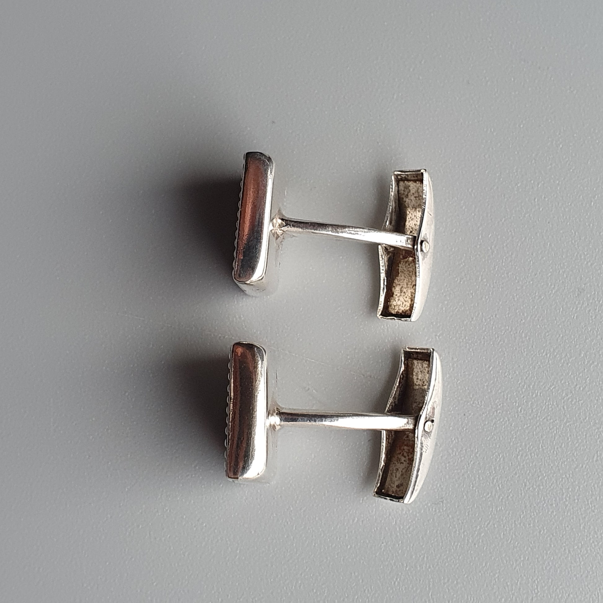 Pair of silver-toned cufflinks with rectangular reddish-brown inlays.