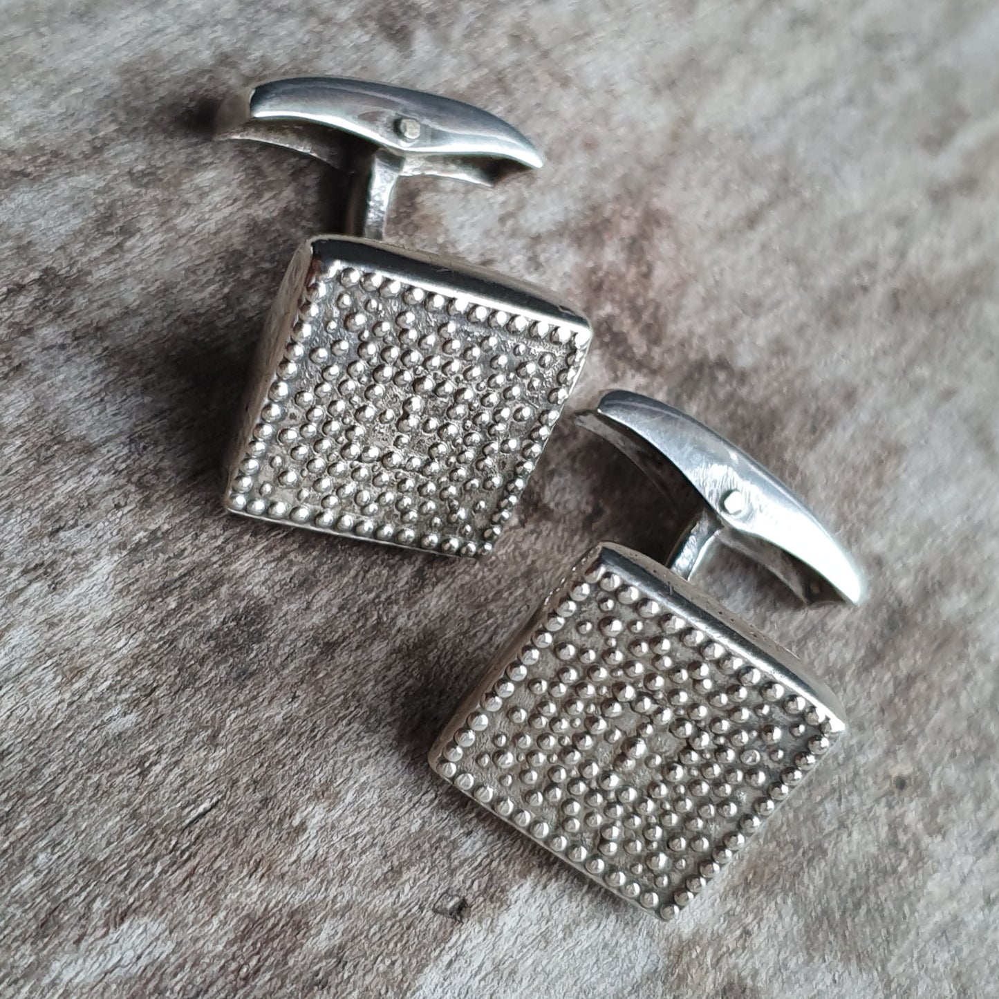 Pair of square silver cufflinks with textured, dotted surfaces.