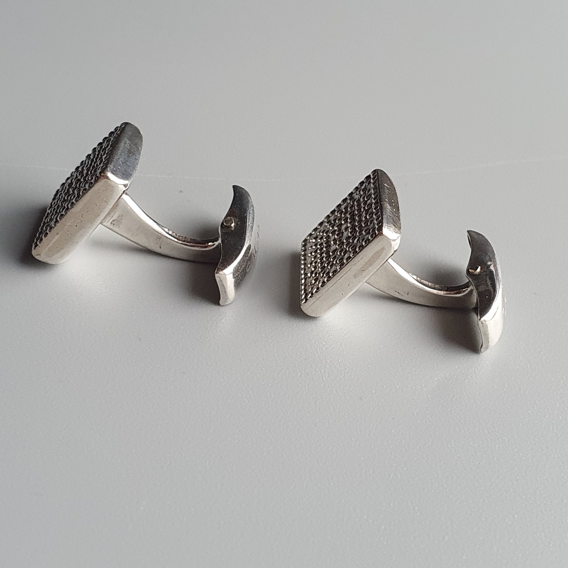 Pair of silver cufflinks with textured rectangular faces.