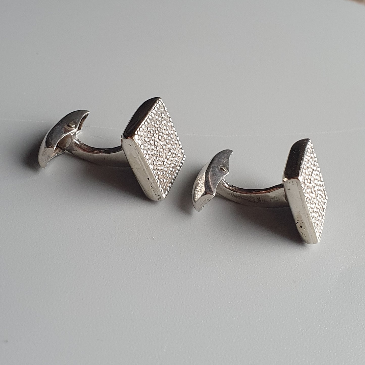 Pair of silver square cufflinks with textured surfaces.